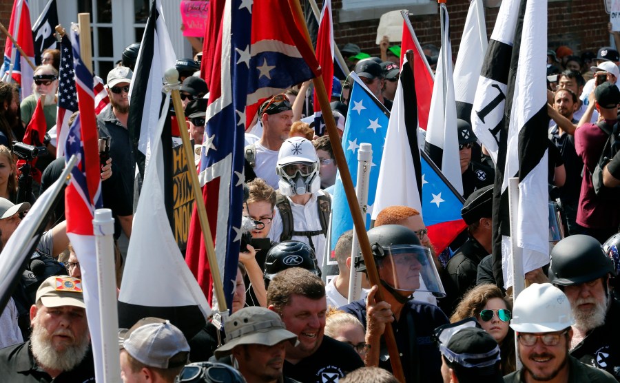 FILE - White nationalist demonstrators walk into the entrance of Lee Park surrounded by counter demonstrators in Charlottesville, Va., Saturday, Aug. 12, 2017.(AP Photo/Steve Helber, File)