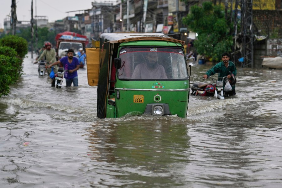 FILE - Motorists drive through a flooded road caused by heavy monsoon rain in Lahore, Pakistan, July 23, 2025. (AP Photo/K.M. Chaudary, File)