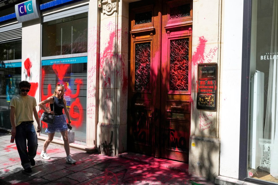 People walk by the vandalized Israeli airline El Al Paris office, with anti-Israel graffiti, Thursday, Aug. 7, 2025 in Paris. (AP Photo/Michel Euler)