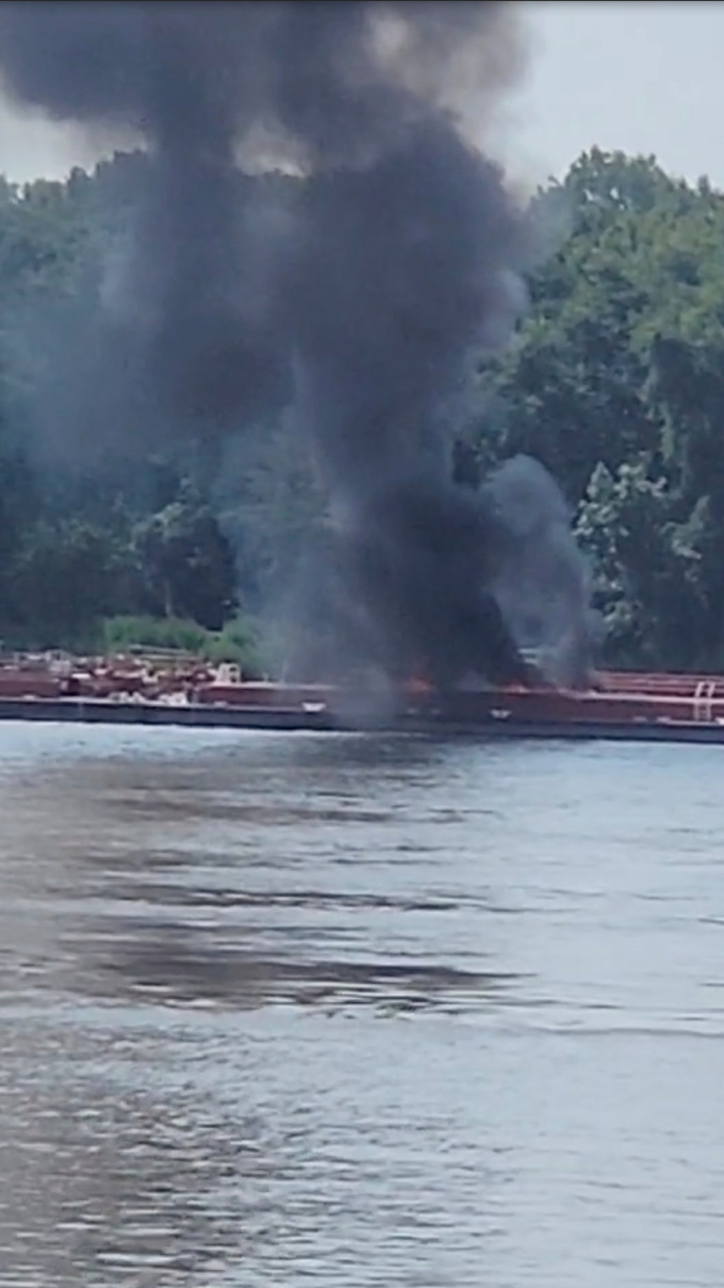 This image provided by Adam Briggs shows smoke fills the air from a barge after a helicopter crash in the Mississippi River near Alton, Ill., on Thursday, Aug. 7, 2025. (Adam Briggs via AP)