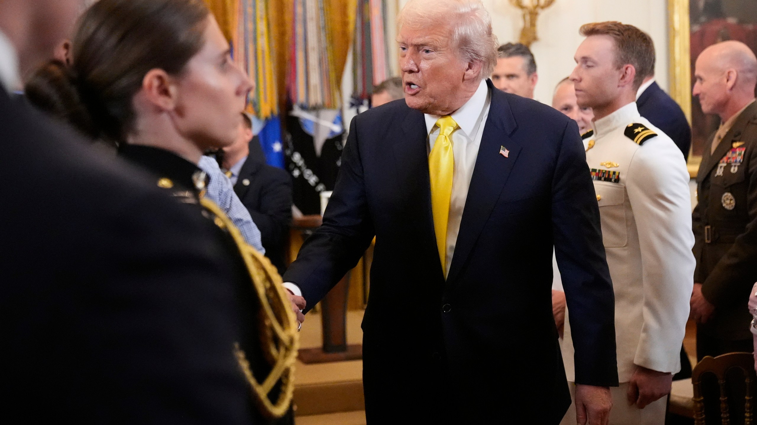 President Donald Trump greets attendees as he departs an event to mark National Purple Heart Day in the East Room of the White House, Thursday, Aug. 7, 2025, in Washington. (AP Photo/Mark Schiefelbein)