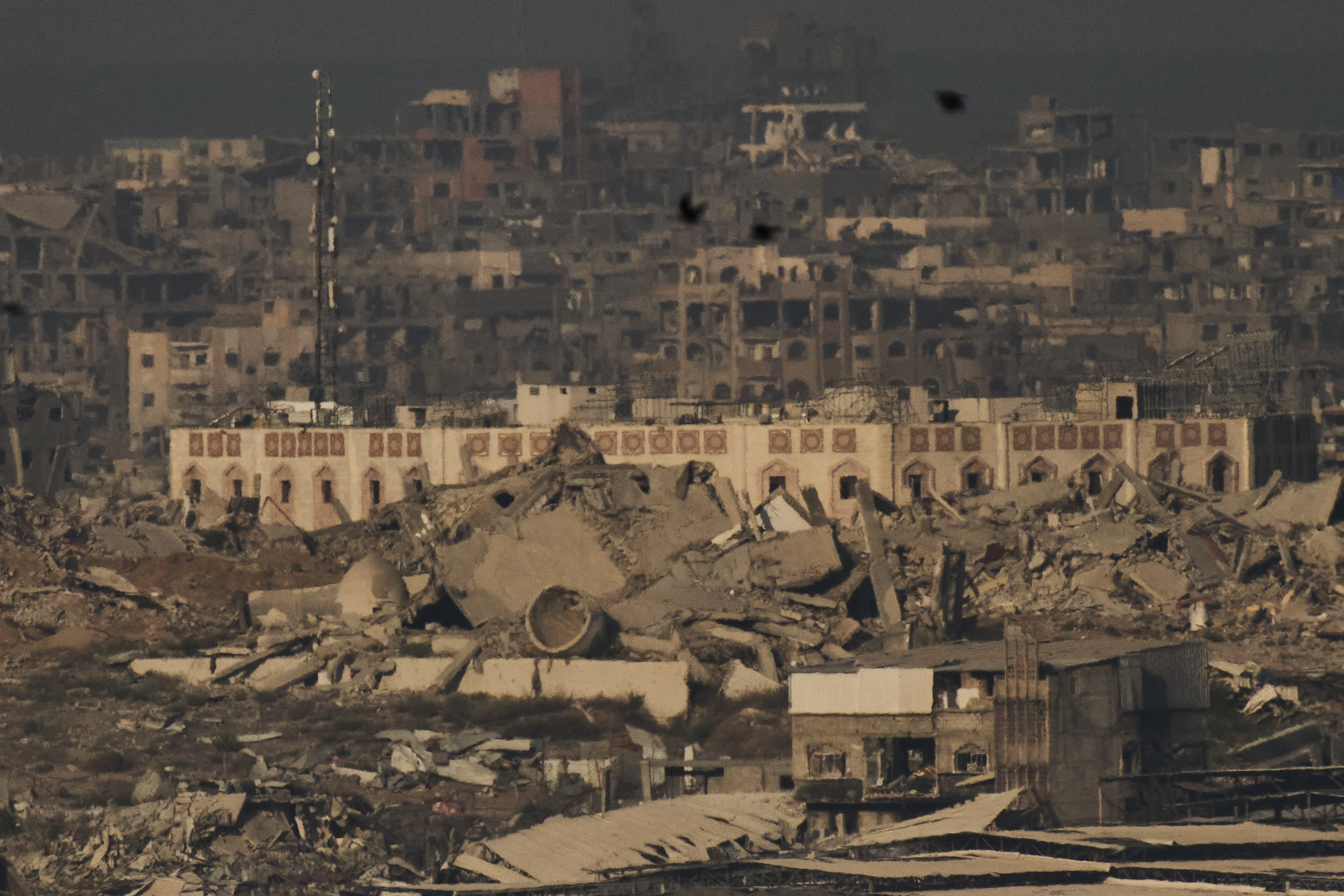 Buildings that were destroyed during the Israeli ground and air operations stand in the northern Gaza Strip during the sunrise, as seen from southern Israel, Friday, Oct. 17, 2025. (AP Photo/Leo Correa)