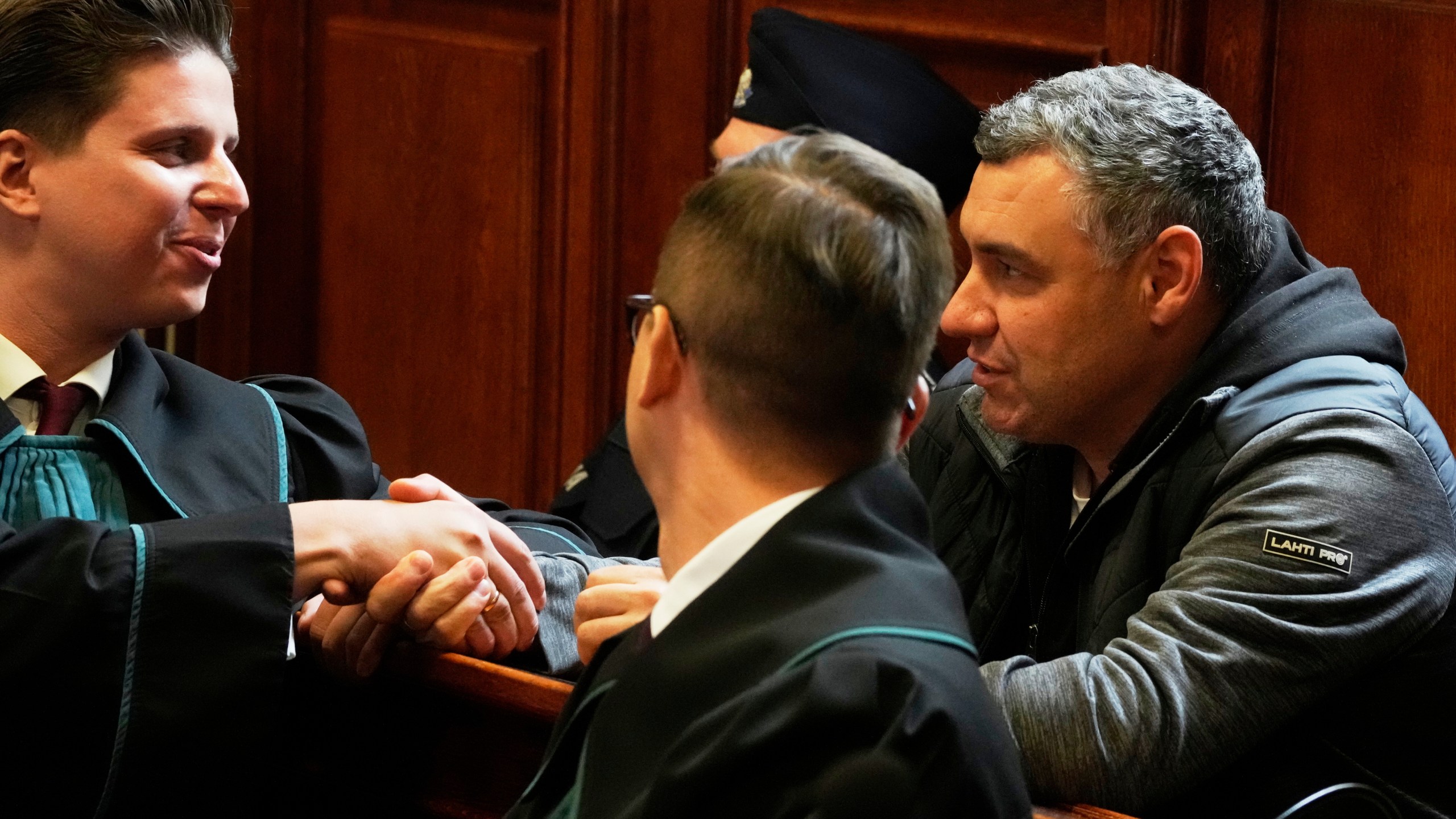 CAPTION CORRECTS THE SPELLING - Ukrainian defendant Volodymyr Zhuravlov, right, shakes hands with his lawyer Tymoteusz Paprocki, left, as a judge announce the decision not to allow for extradition to Germany in courtroom of Warsaw's Regional Court in Warsaw, Poland, Friday, Oct. 17, 2025. (AP Photo/Czarek Sokolowski)