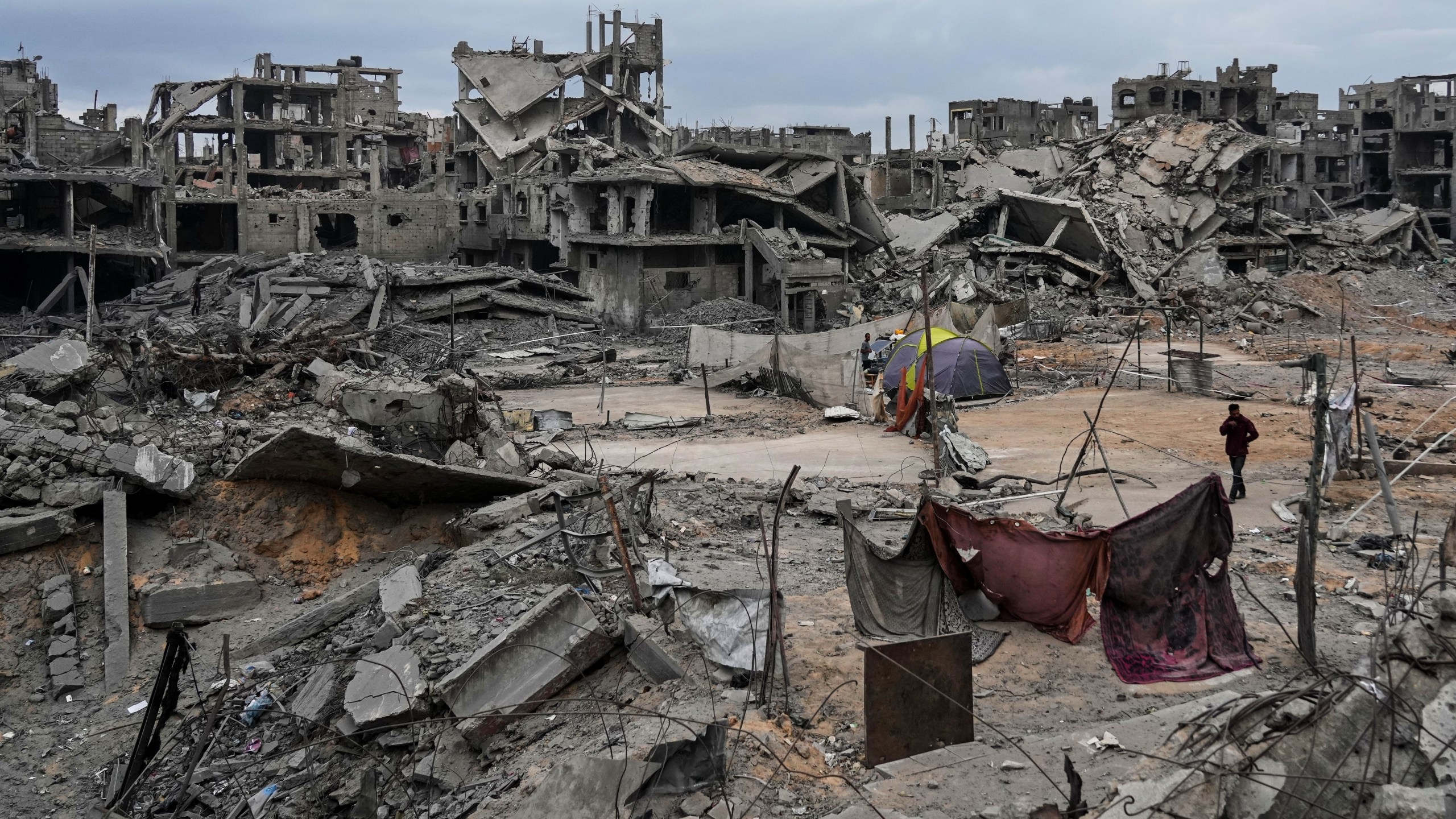 Displaced Palestinians set up their tents amid destroyed buildings at the Shati refugee camp in Gaza City, Sunday, Oct. 12, 2025, after Israel and Hamas agreed to a pause in their war and the release of the remaining hostages. (AP Photo/Abdel Kareem Hana)
