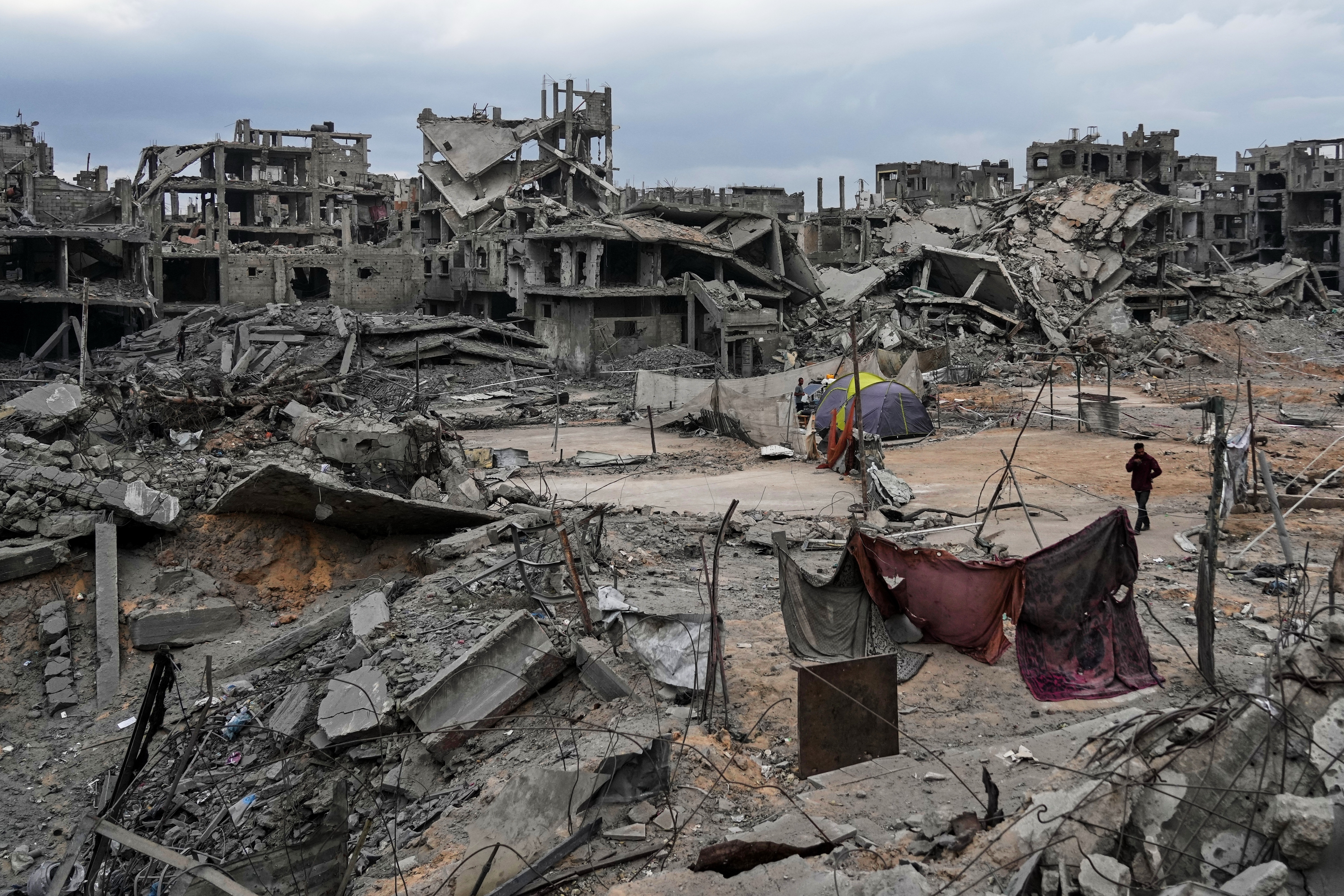 Displaced Palestinians set up their tents amid destroyed buildings at the Shati refugee camp in Gaza City, Sunday, Oct. 12, 2025, after Israel and Hamas agreed to a pause in their war and the release of the remaining hostages. (AP Photo/Abdel Kareem Hana)