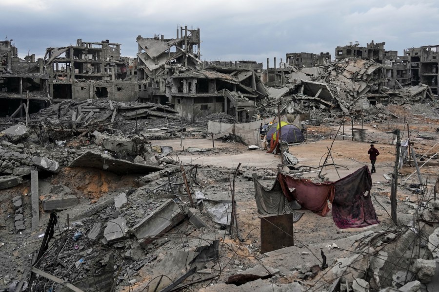 Displaced Palestinians set up their tents amid destroyed buildings at the Shati refugee camp in Gaza City, Sunday, Oct. 12, 2025, after Israel and Hamas agreed to a pause in their war and the release of the remaining hostages. (AP Photo/Abdel Kareem Hana)