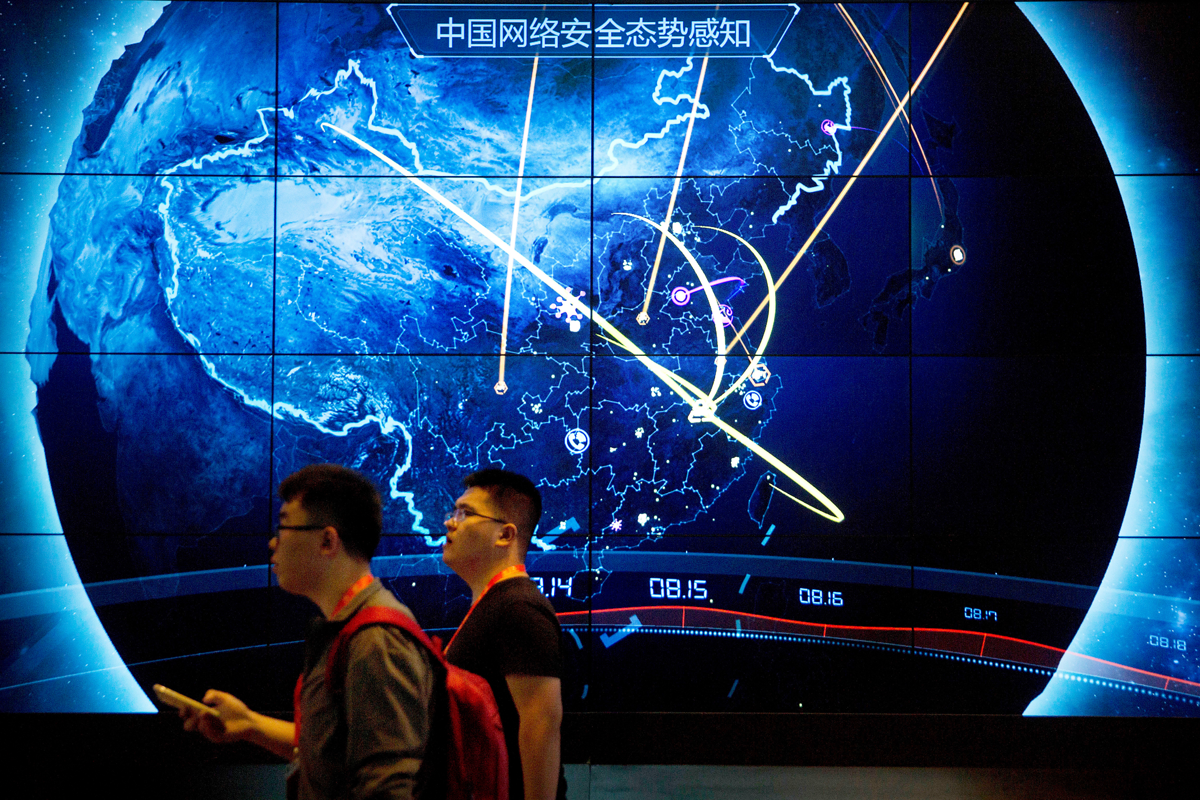 FILE - Attendees walk past an electronic display showing recent cyberattacks in China at the China Internet Security Conference in Beijing on Sept. 12, 2017. (AP Photo/Mark Schiefelbein, File)