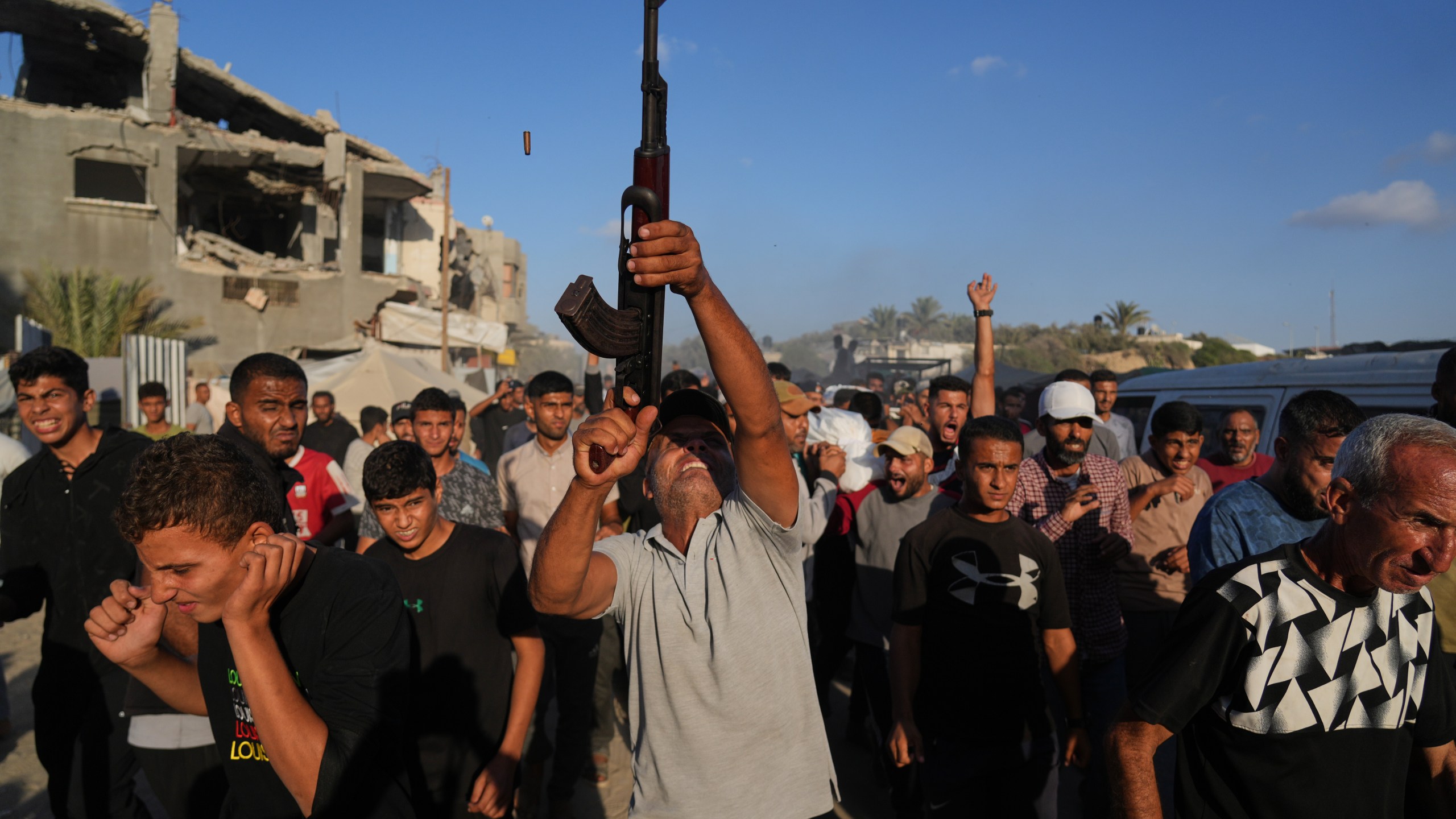 An armed man shoots in the air during the funeral of Palestinians killed by Israeli fire, in Deir al-Balah, Gaza Strip, Sunday, Oct. 19, 2025. (AP Photo/Abdel Kareem Hana)