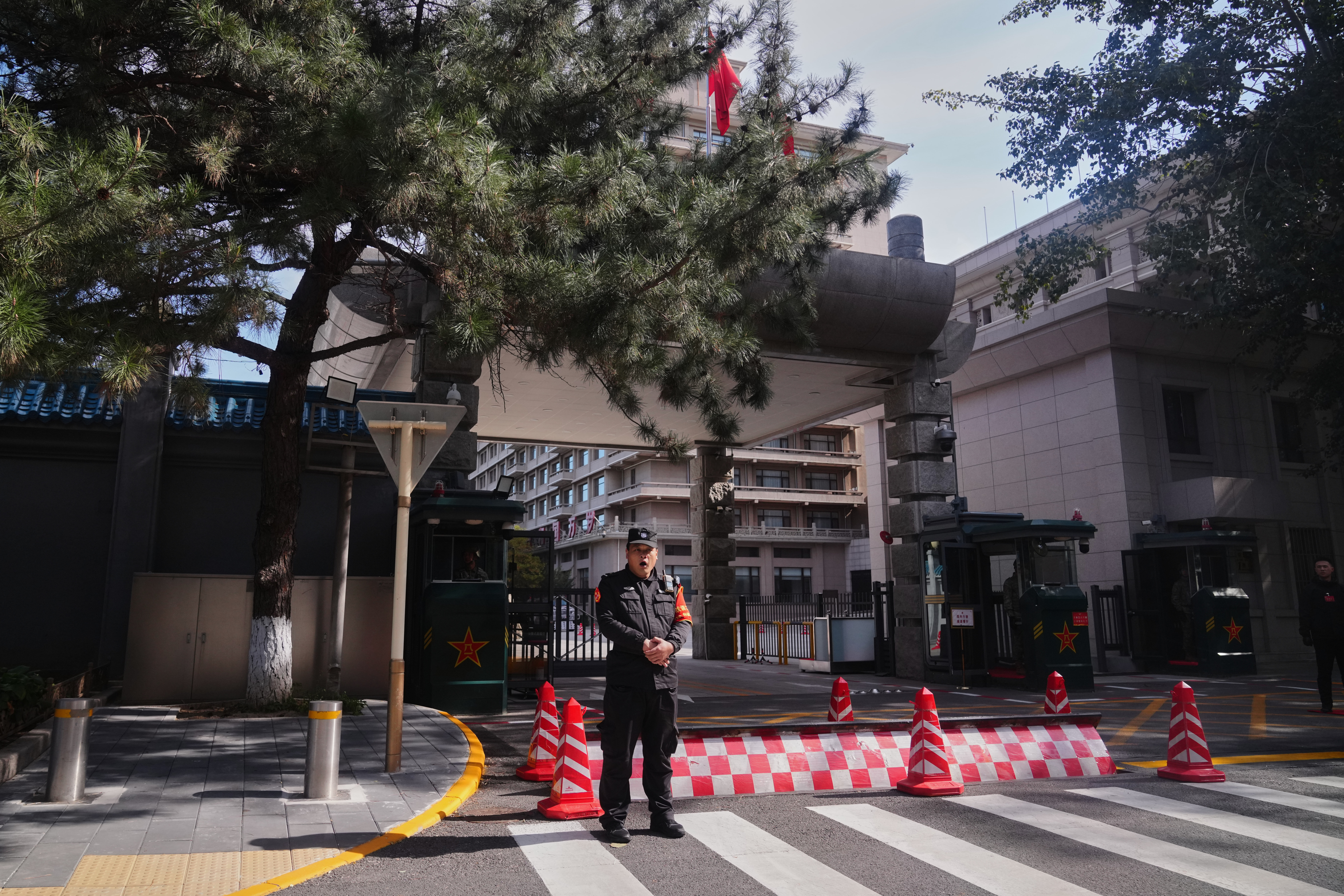 A Chinese security person yawns as he stands guard at the entrance gate to the Jingxi Hotel where the Communist Party's Central Committee is holding its fourth plenum, in Beijing, Monday, Oct. 20, 2025. (AP Photo/Andy Wong)