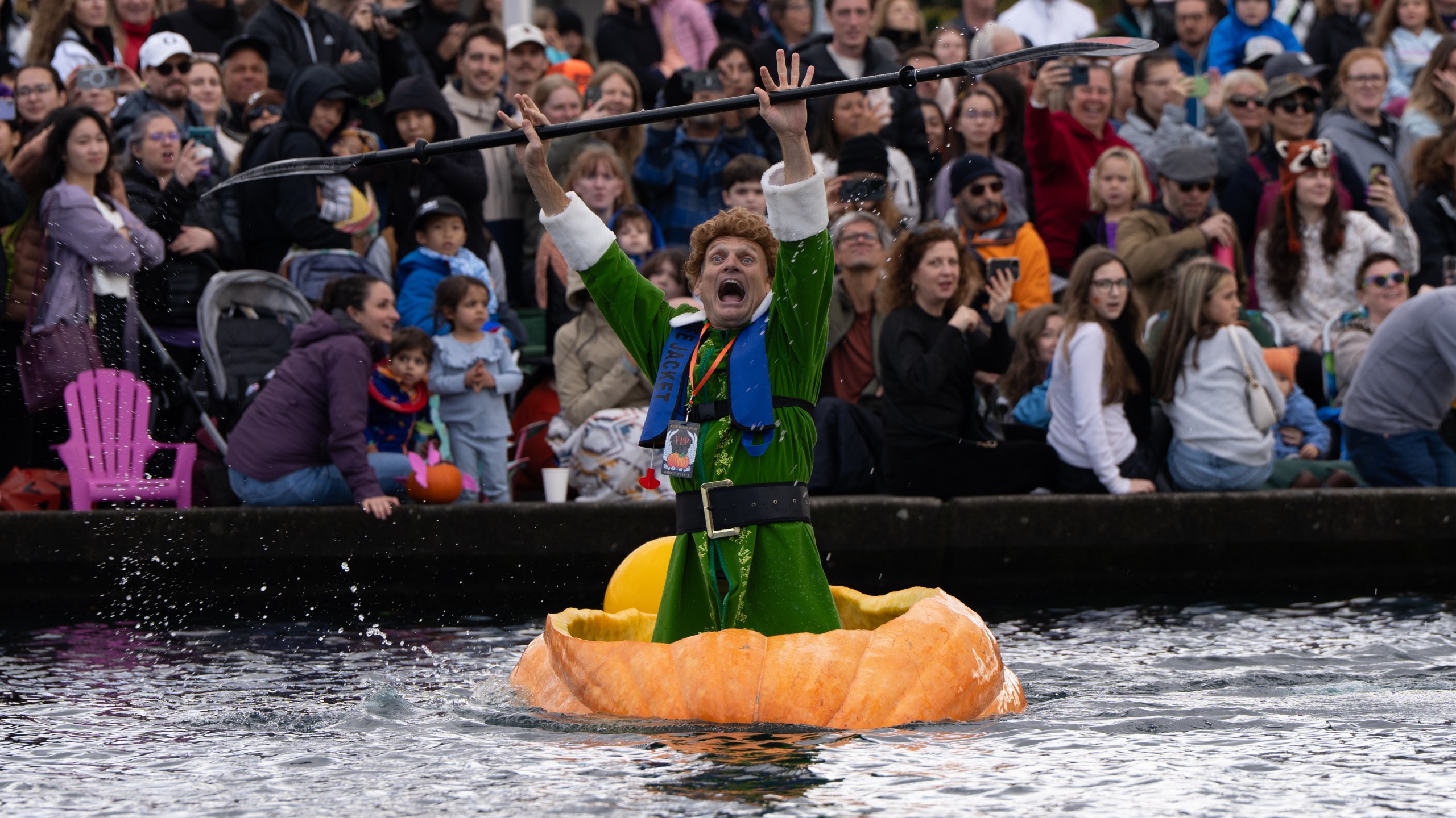 Gary Kristensen, dressed up as the character Buddy from the holiday movie "Elf," celebrates after winning a race during the West Coast Giant Pumpkin Regatta on Sunday, Oct. 19, 2025, in Tualatin, Ore. (AP Photo/Jenny Kane)