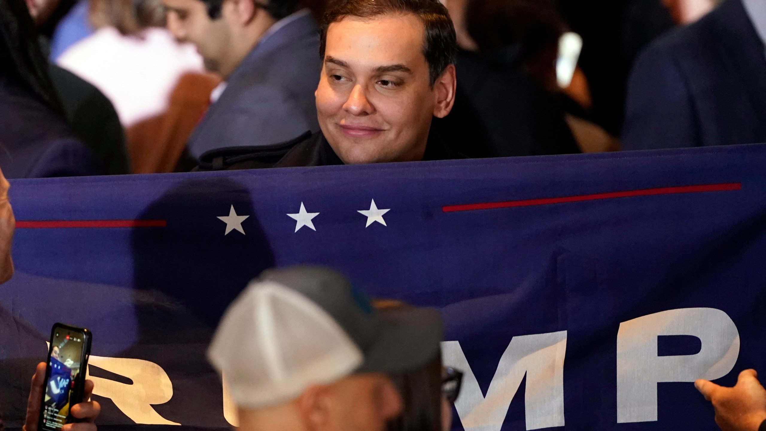 FILE - Former Rep George Santos, R-N.Y., holds a sign before Republican presidential candidate former President Donald Trump speaks at a primary election night party in Nashua, N.H., Jan. 23, 2024. (AP Photo/Pablo Martinez Monsivais, file)