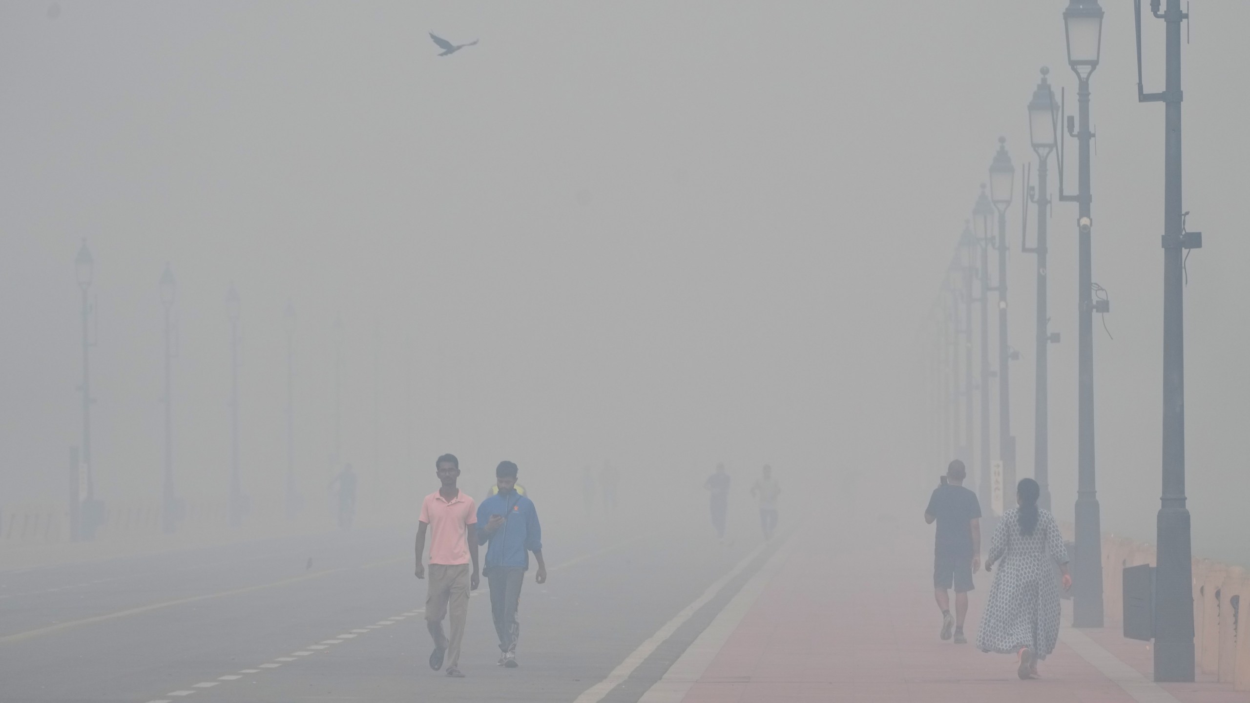 People walk in the morning near the India Gate monument amidst morning smog a day after Diwali festival in New Delhi, India, Tuesday, Oct. 21, 2025. (AP Photo/Manish Swarup)