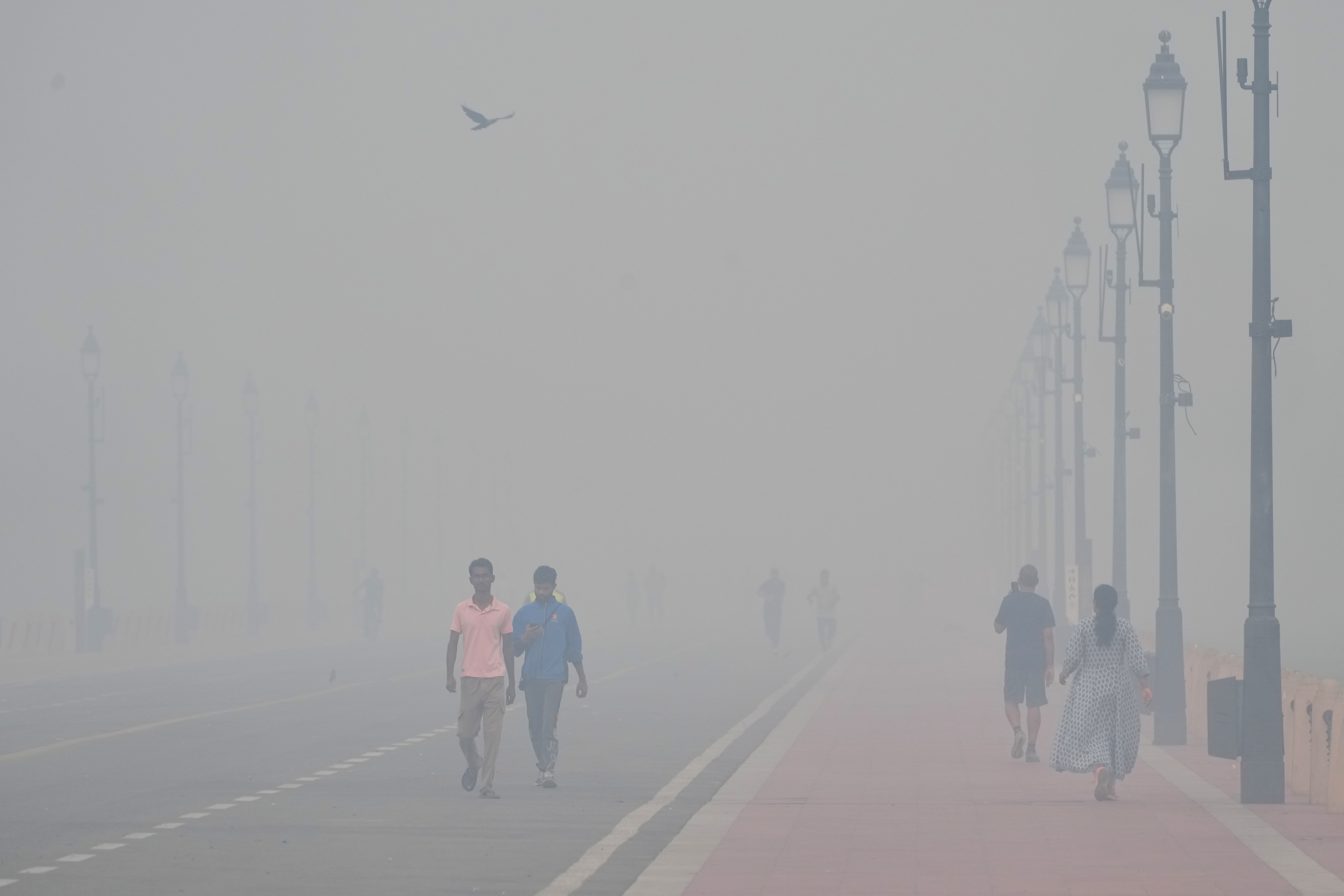 People walk in the morning near the India Gate monument amidst morning smog a day after Diwali festival in New Delhi, India, Tuesday, Oct. 21, 2025. (AP Photo/Manish Swarup)