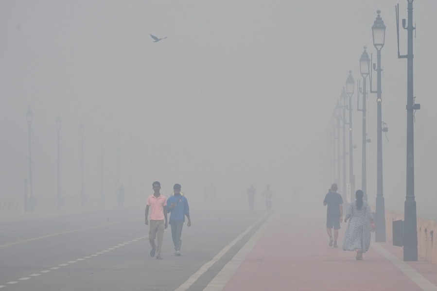 People walk in the morning near the India Gate monument amidst morning smog a day after Diwali festival in New Delhi, India, Tuesday, Oct. 21, 2025. (AP Photo/Manish Swarup)