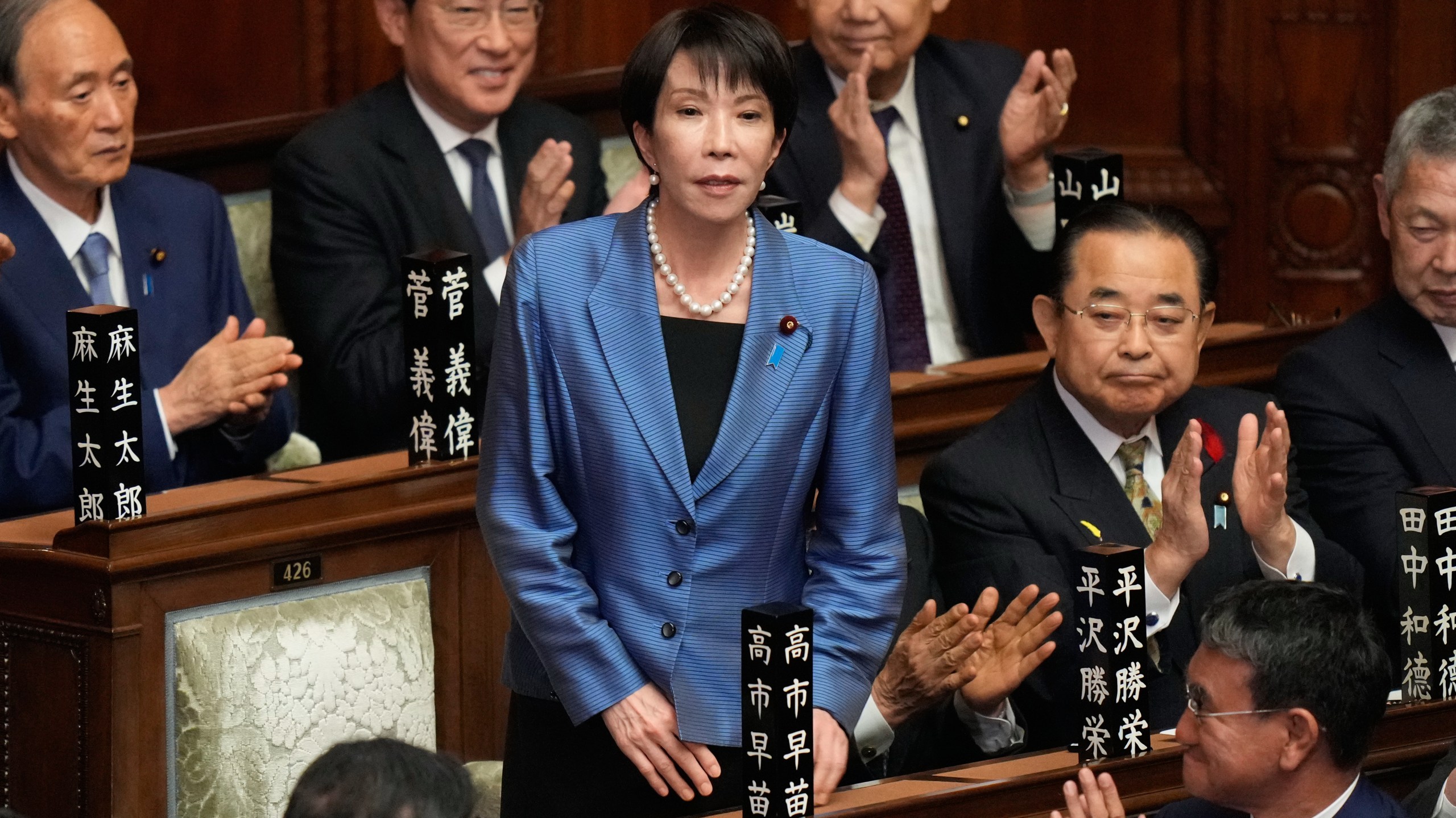 Lawmakers applaud as Sanae Takaichi, standing, was elected as Japan's new prime minister during the extraordinary session of the lower house, in Tokyo, Japan, Tuesday, Oct. 21, 2025.(AP Photo/Eugene Hoshiko)