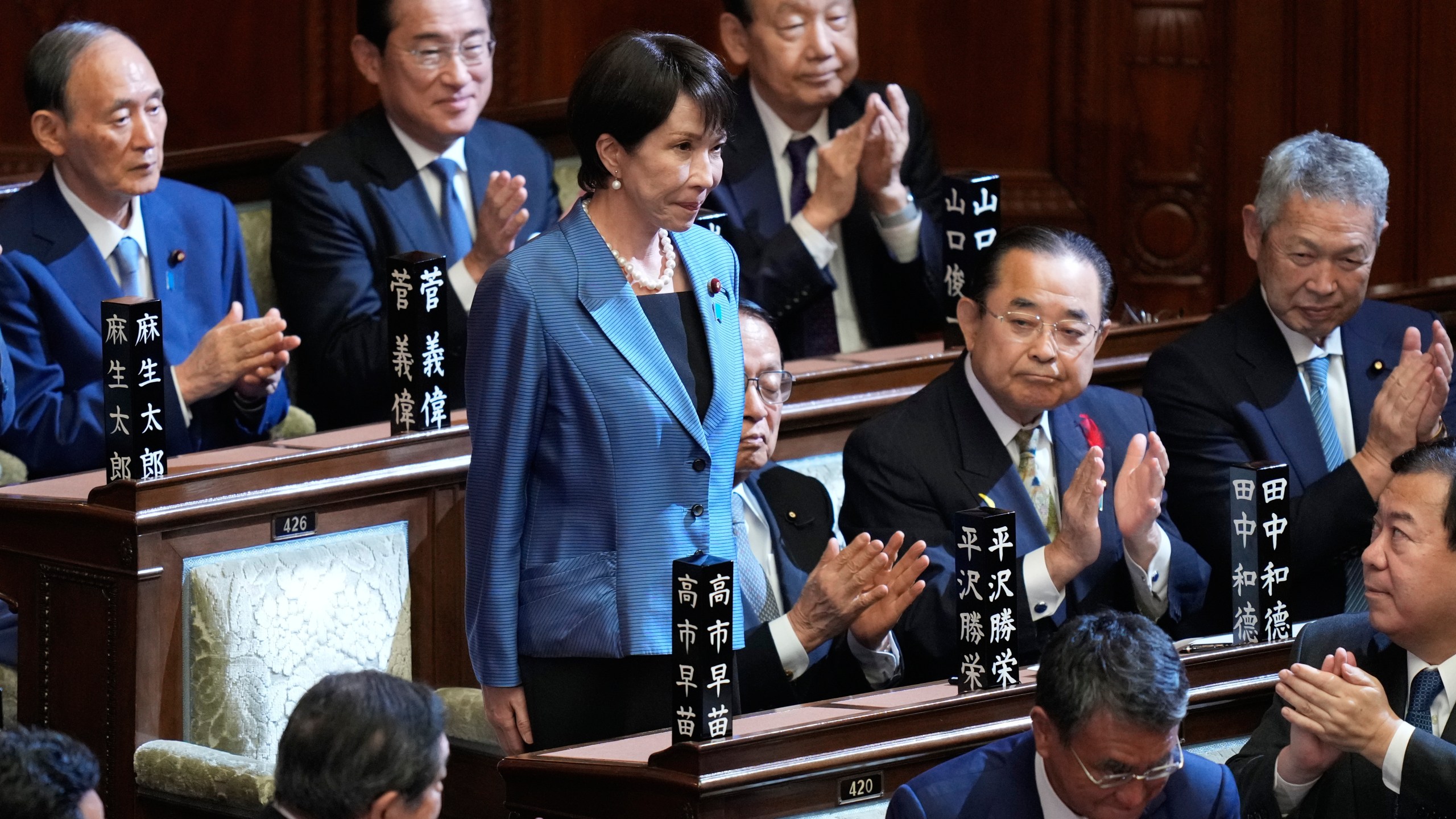 Lawmakers applaud as Sanae Takaichi, standing, was elected as Japan's new prime minister during the extraordinary session of the lower house, in Tokyo, Japan, Tuesday, Oct. 21, 2025.(AP Photo/Eugene Hoshiko)