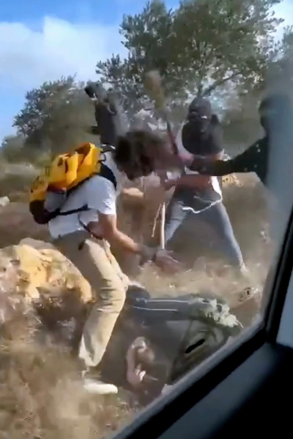 This Oct. 19, 2025, image taken from video shows what appear to be masked settlers beating activists and Palestinian farmers in Turmus Ayya, West Bank. (AP Photo)