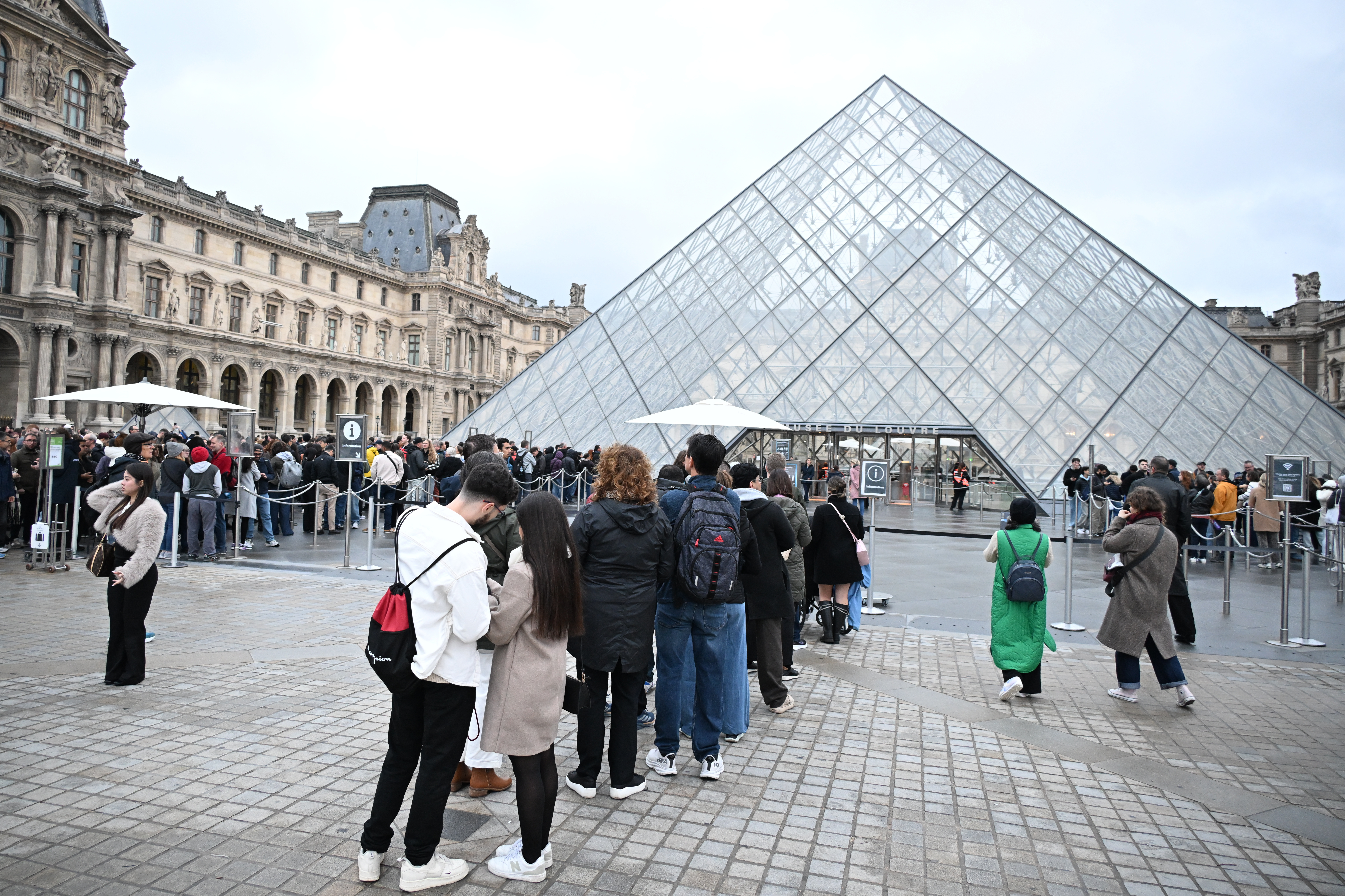 People queue outside the Louvre museum in Paris on Monday, Oct. 20, 2025, although it remains closed for the day after Sunday's jewels robbery. (AP Photo/Emma Da Silva)