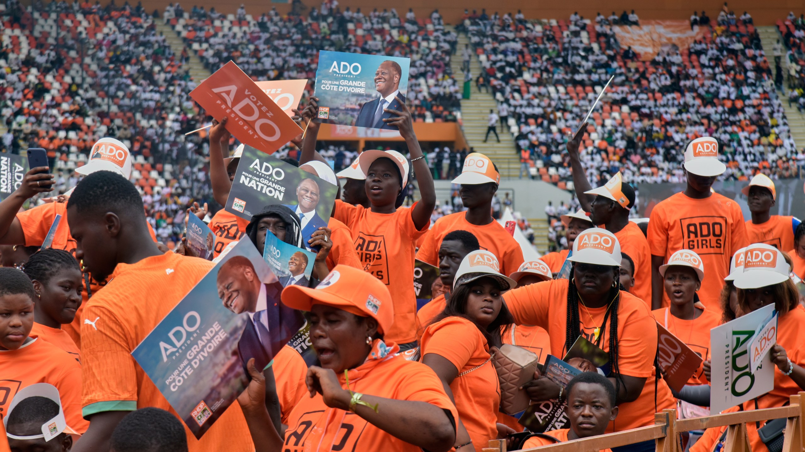 Supporters of President Alassane Ouattara hold posters during a campaign rally at the Félix Houphouët-Boigny Stadium in Abidjan, Ivory Coast, Saturday, Oct. 18, 2025. (AP Photo/Diomande Ble Blonde)