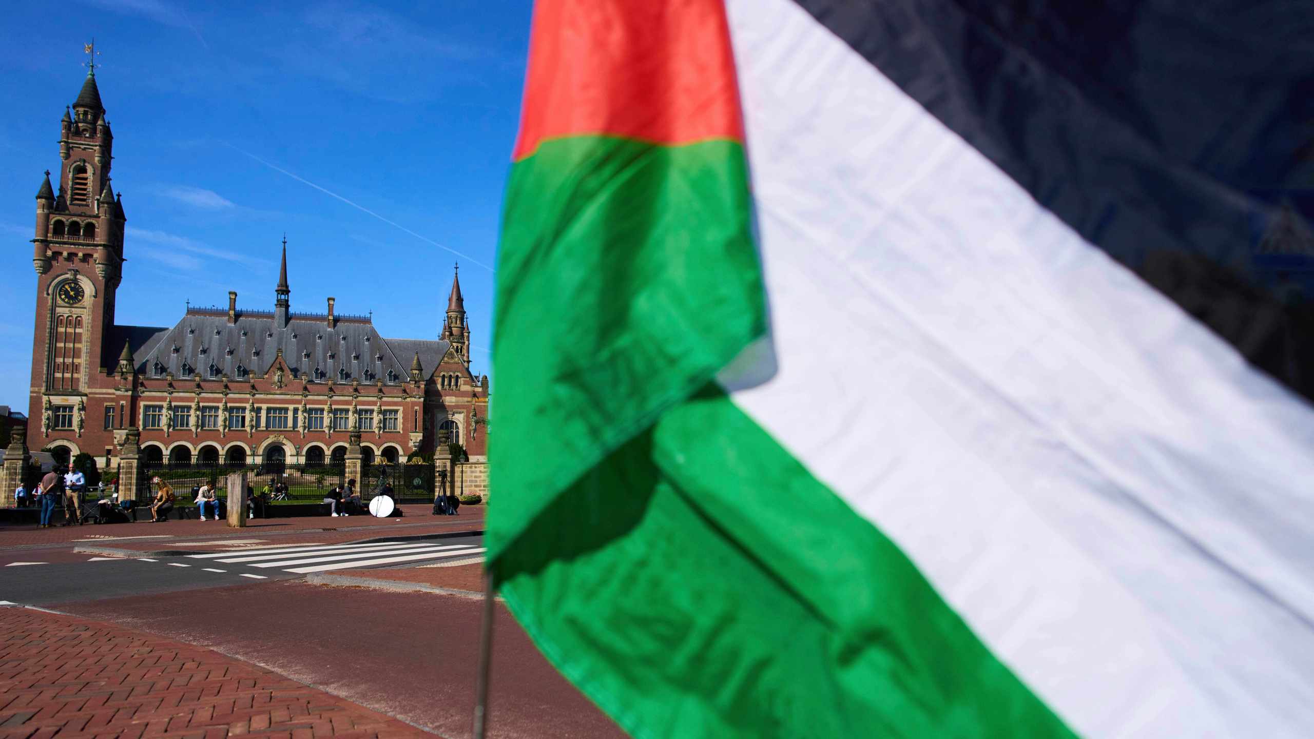 FILE -A Palestinian flag flies outside the International Court of Justice, rear, which opened hearings into a United Nations request for an advisory opinion on Israel's obligations to allow humanitarian assistance in Gaza and the West Bank, in The Hague, Netherlands, April 28, 2025. (AP Photo/Peter Dejong, File)