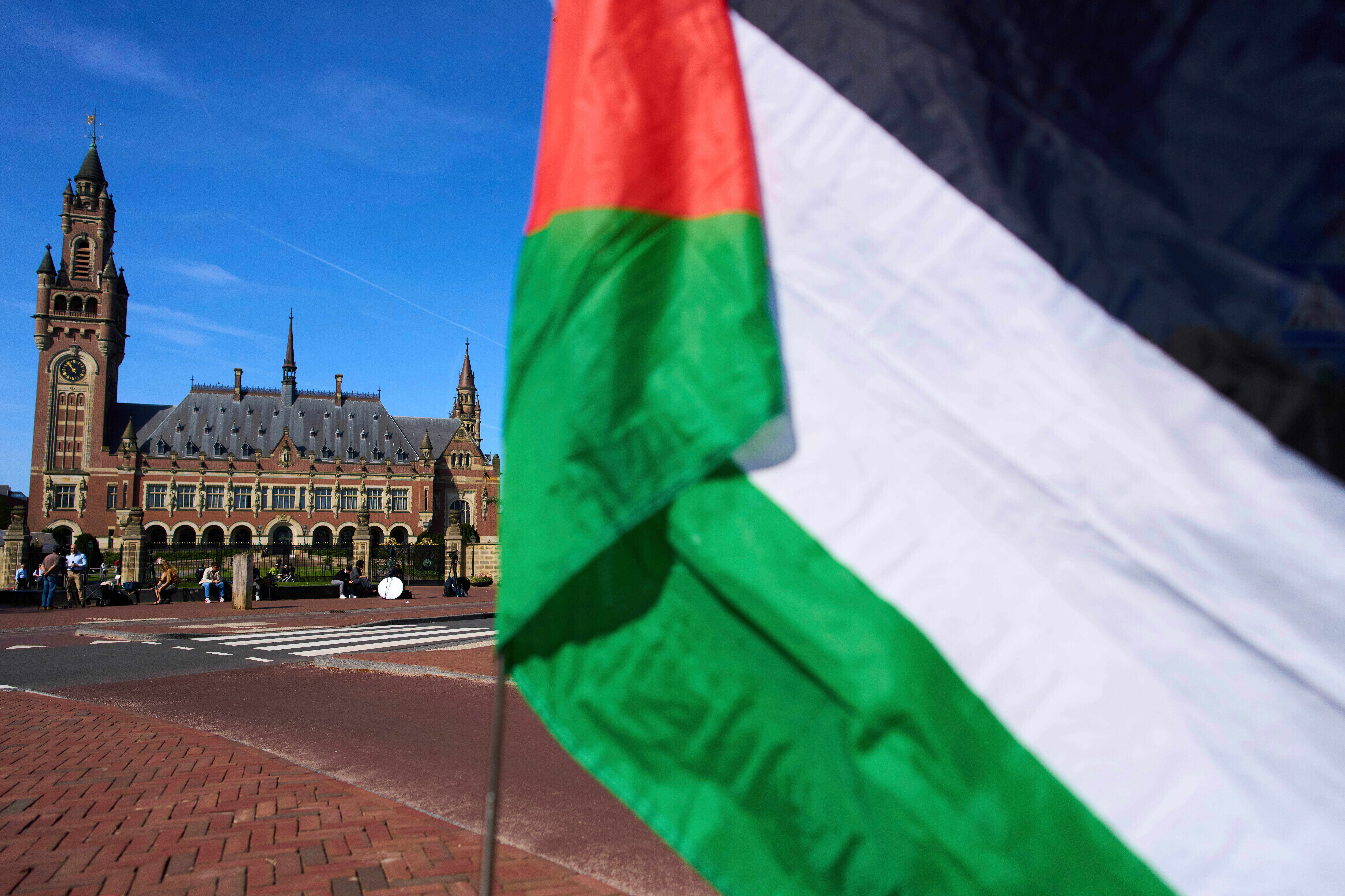 FILE -A Palestinian flag flies outside the International Court of Justice, rear, which opened hearings into a United Nations request for an advisory opinion on Israel's obligations to allow humanitarian assistance in Gaza and the West Bank, in The Hague, Netherlands, April 28, 2025. (AP Photo/Peter Dejong, File)