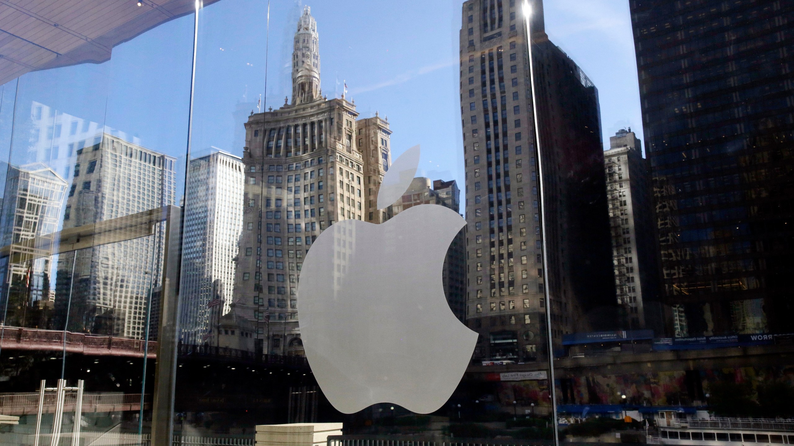 FILE - Buildings are reflected behind the logo at an Apple Store, in downtown Chicago, Oct. 19, 2017. (AP Photo/Kiichiro Sato, File)