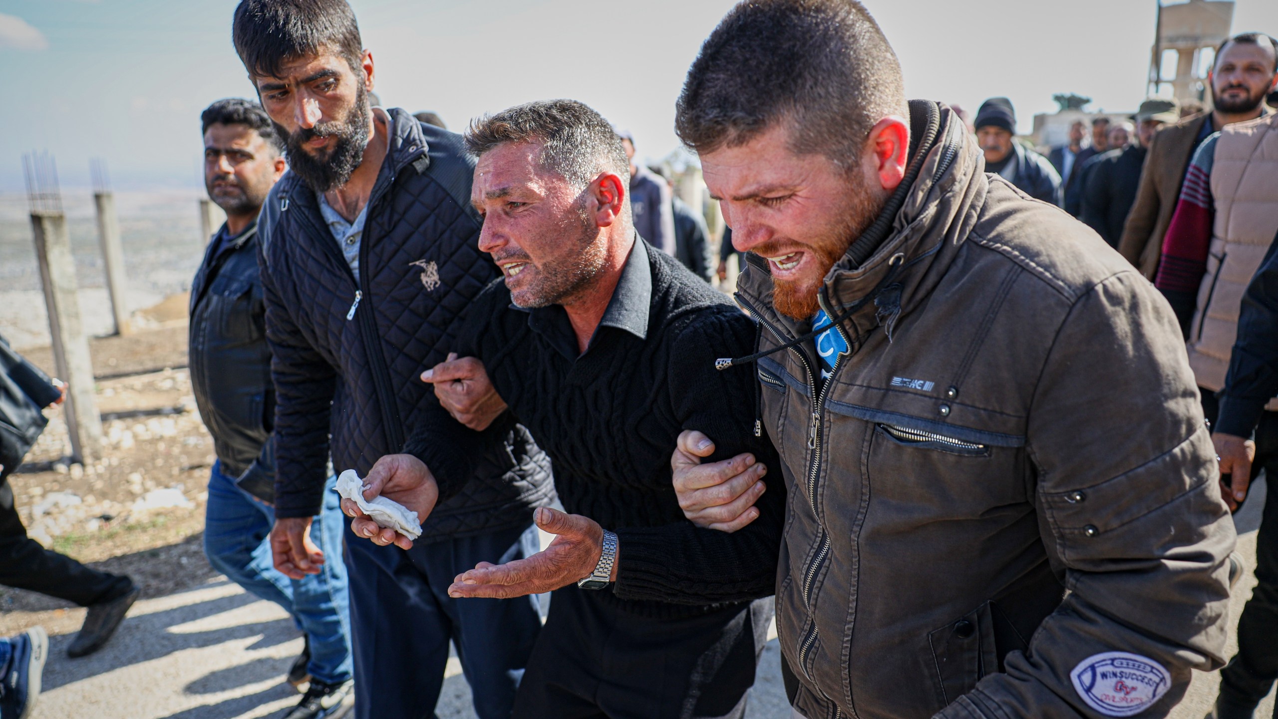 Men weep as they follow the funeral procession of three people killed when gunmen on motorcycles fired on a van near the Druze village of Kafr Maris in Syria's Idlib province, Wednesday, Oct. 22, 2025. (AP Photo/Omar Albam)