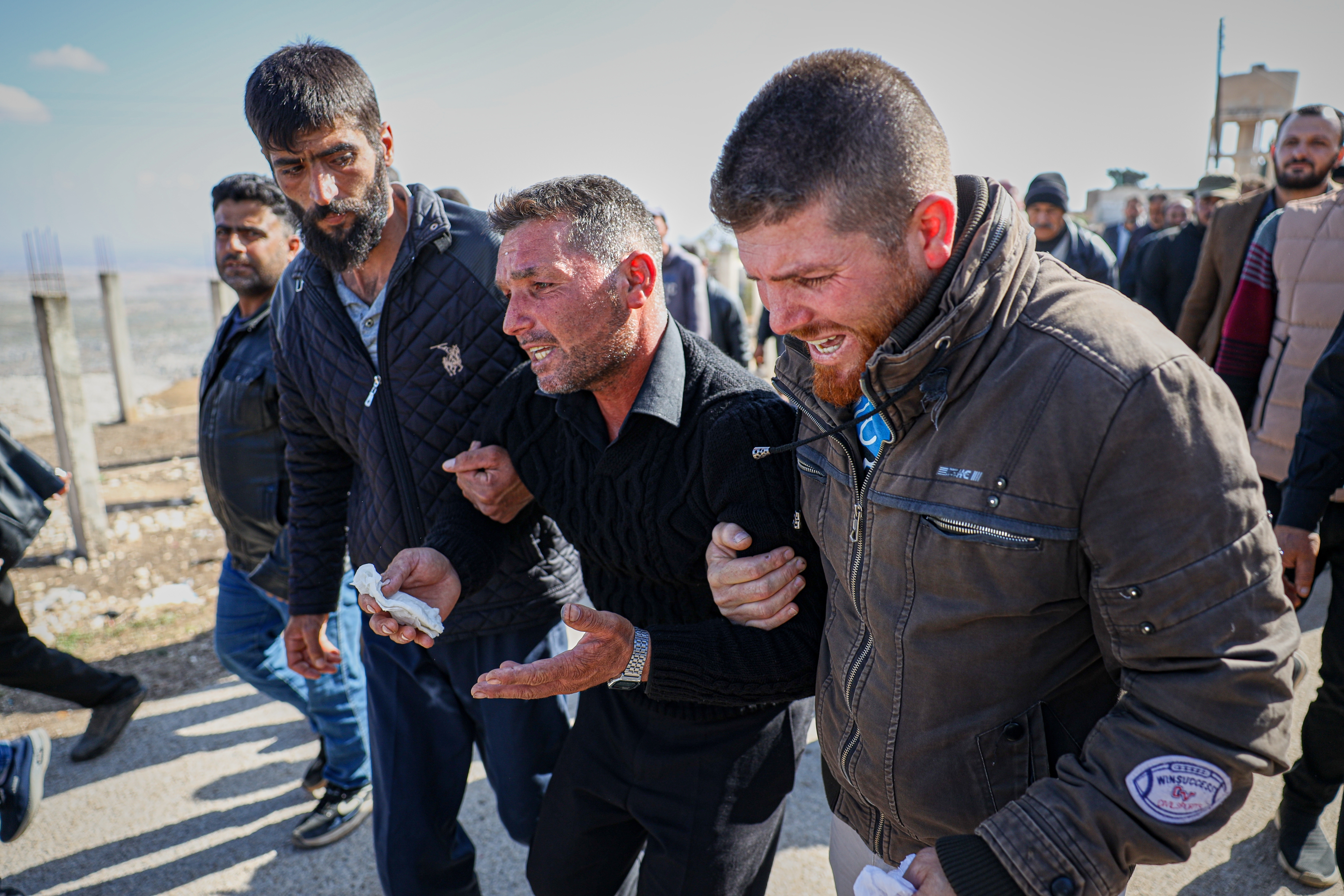 Men weep as they follow the funeral procession of three people killed when gunmen on motorcycles fired on a van near the Druze village of Kafr Maris in Syria's Idlib province, Wednesday, Oct. 22, 2025. (AP Photo/Omar Albam)