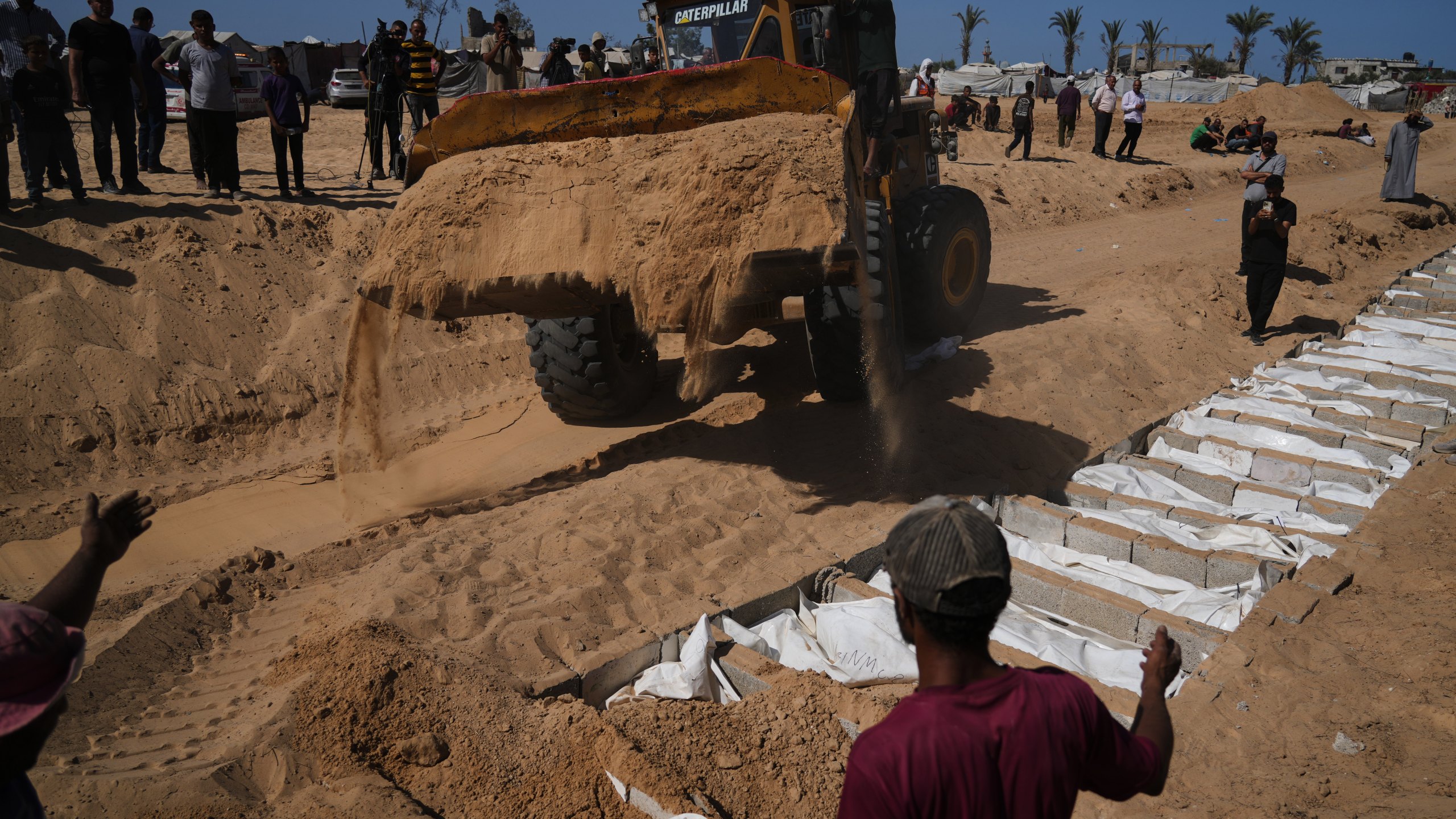 Bodies of unidentified Palestinians returned from Israel as part of the ceasefire deal are buried in a mass grave in Deir al-Balah, Gaza Strip, Wednesday, Oct. 22, 2025. (AP Photo/Jehad Alshrafi)