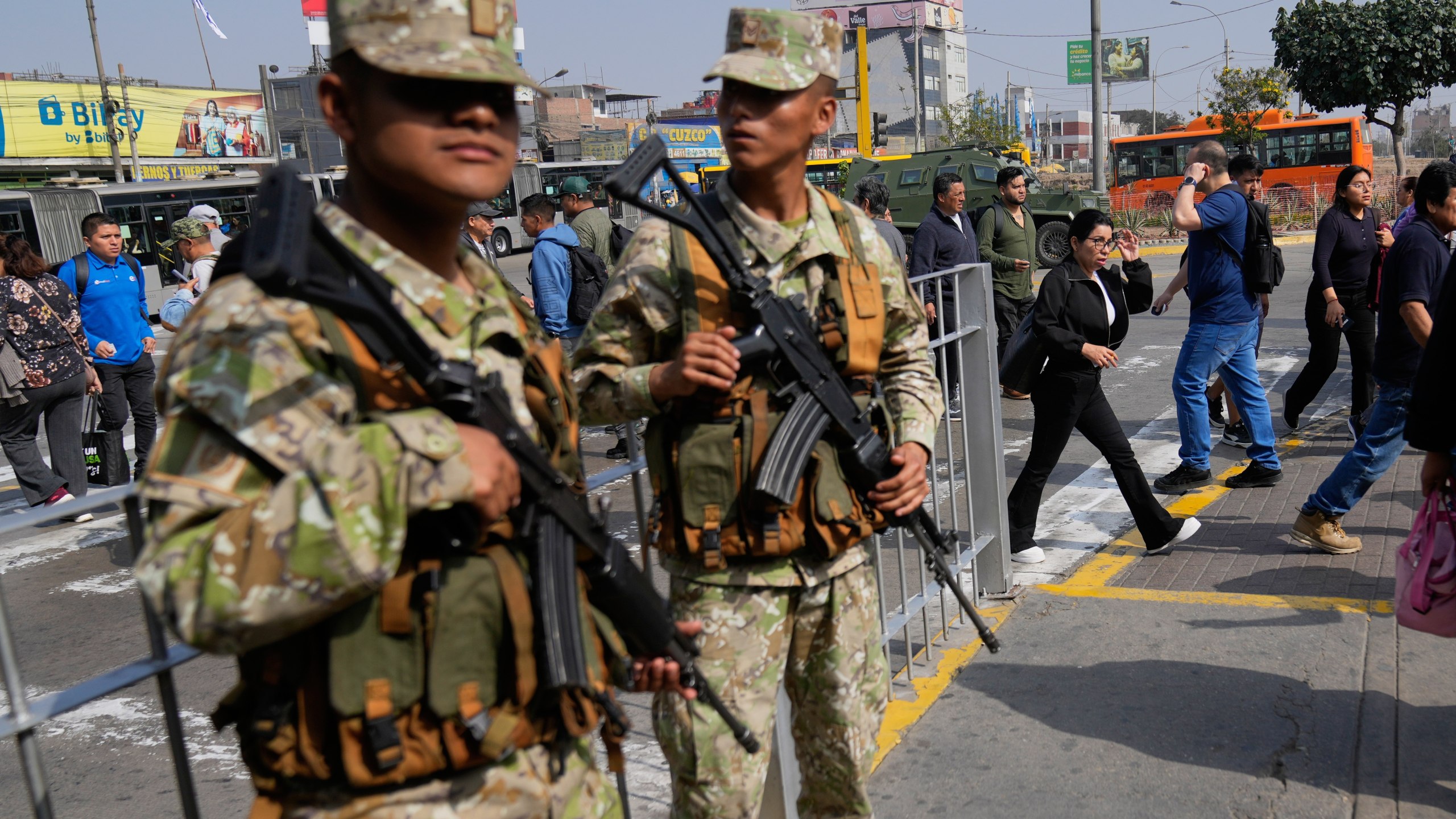 Pedestrians walk past soldiers standing guard in Lima, Peru, Wednesday, Oct. 22, 2025, after President Jose Jeri declared a state of emergency. (AP Photo/Martin Mejia)