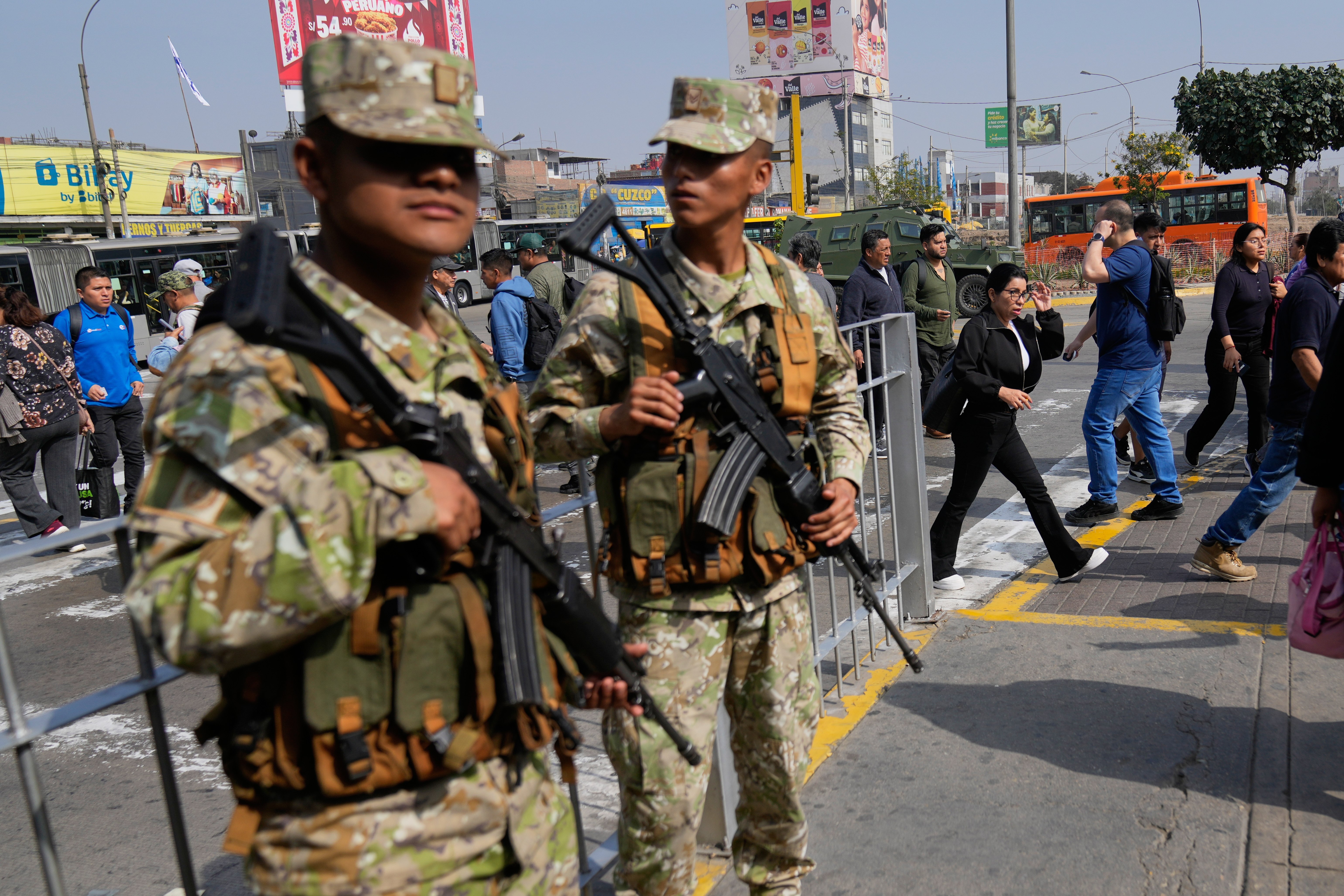 Pedestrians walk past soldiers standing guard in Lima, Peru, Wednesday, Oct. 22, 2025, after President Jose Jeri declared a state of emergency. (AP Photo/Martin Mejia)