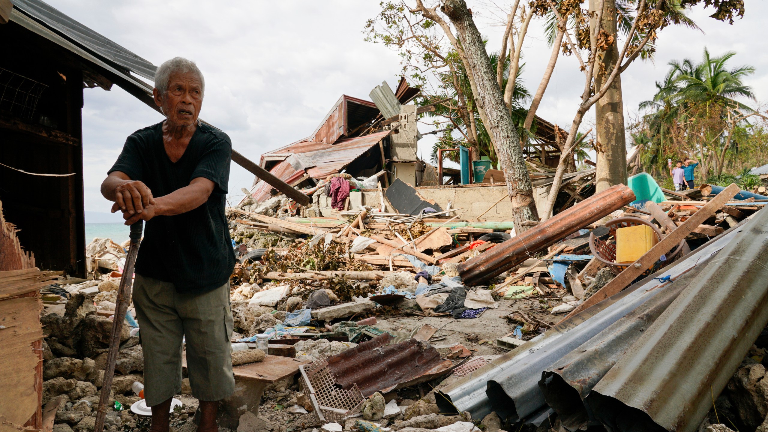 FILE -Bernardino Aspacio walks past rubbles from his damaged house due to Typhoon Rai in Alegria, Cebu province, central Philippines, Dec. 22, 2021. (AP Photo/Jay Labra, File)