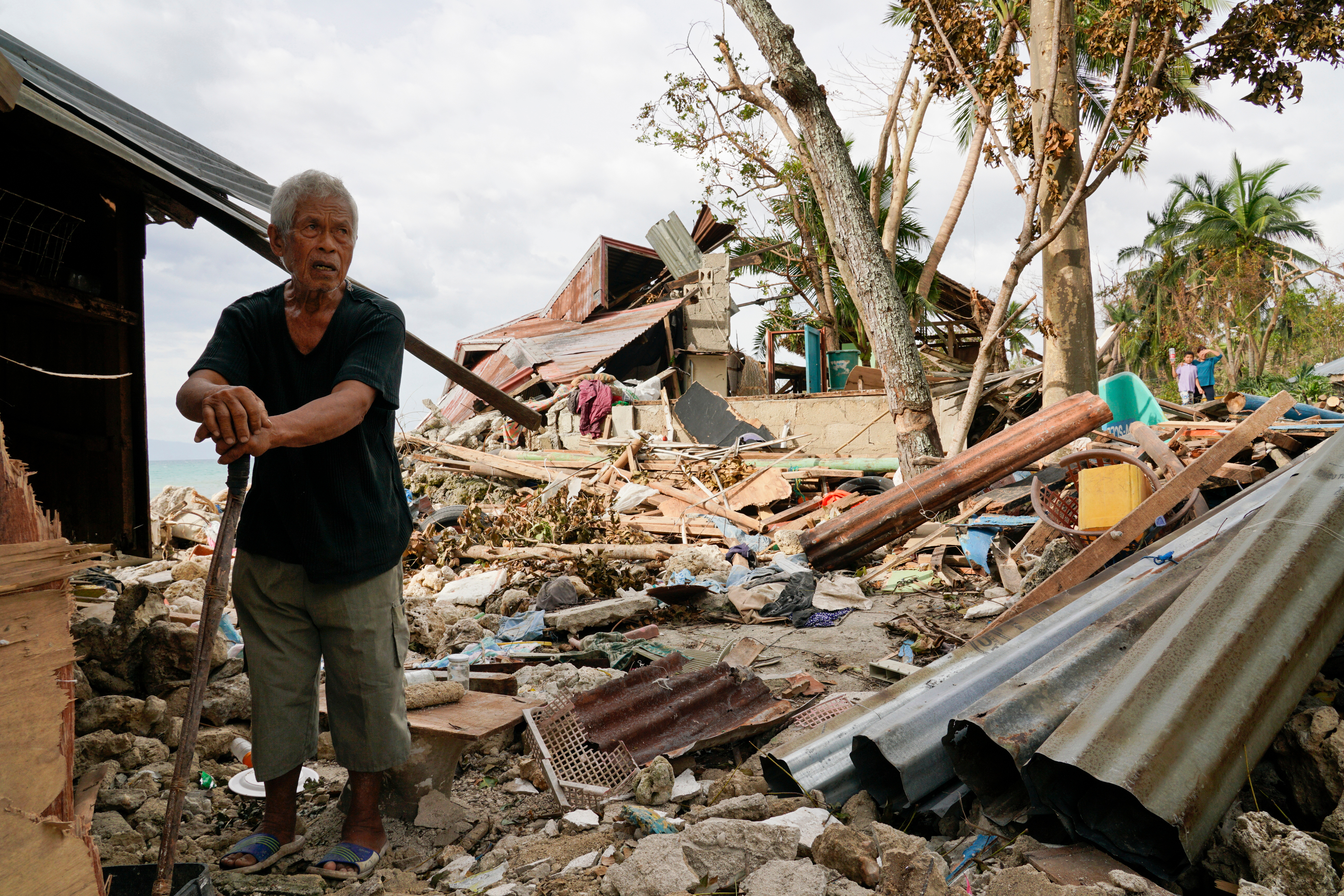 FILE -Bernardino Aspacio walks past rubbles from his damaged house due to Typhoon Rai in Alegria, Cebu province, central Philippines, Dec. 22, 2021. (AP Photo/Jay Labra, File)