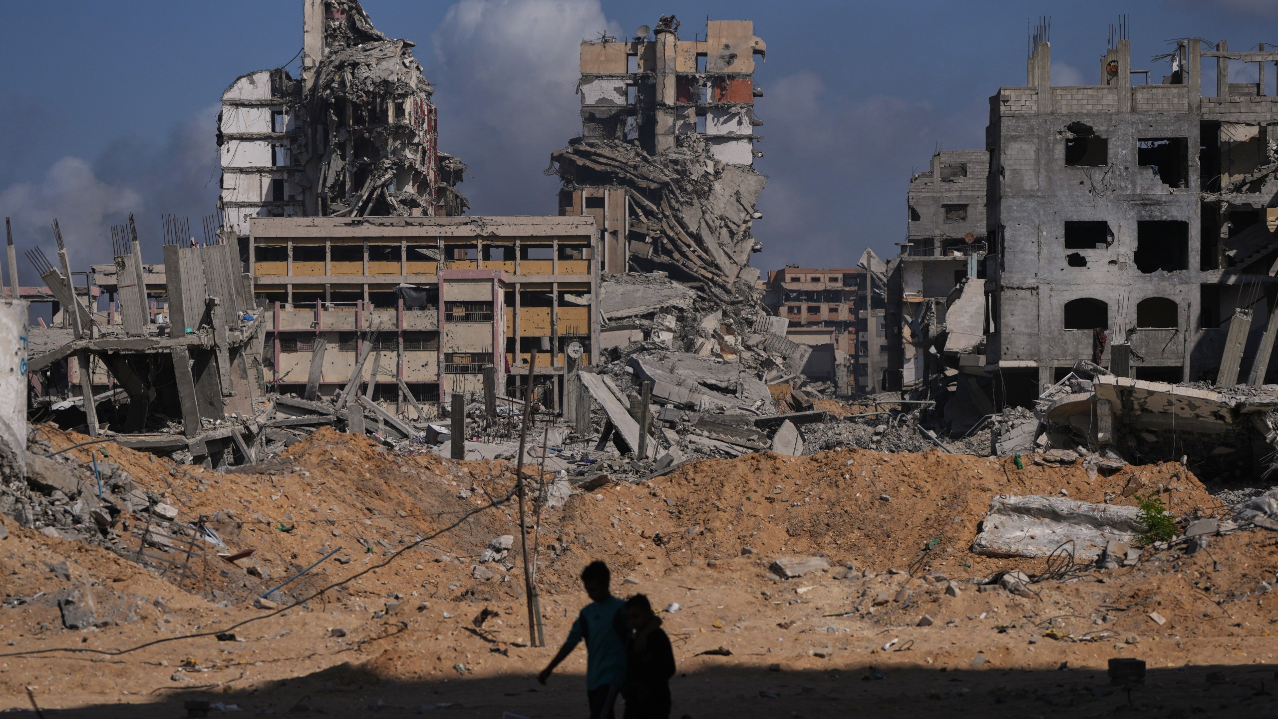 Palestinians walk through the destruction caused by the Israeli air and ground offensive in the Al-Shati camp, in Gaza City, Friday, Oct. 24, 2025. (AP Photo/Abdel Kareem Hana)
