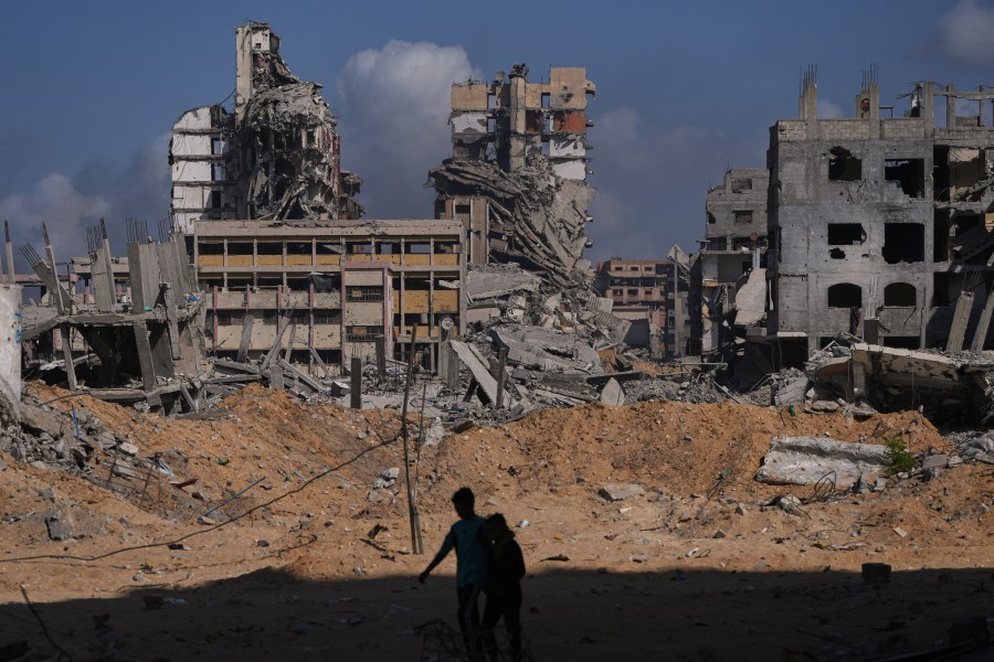 Palestinians walk through the destruction caused by the Israeli air and ground offensive in the Al-Shati camp, in Gaza City, Friday, Oct. 24, 2025. (AP Photo/Abdel Kareem Hana)