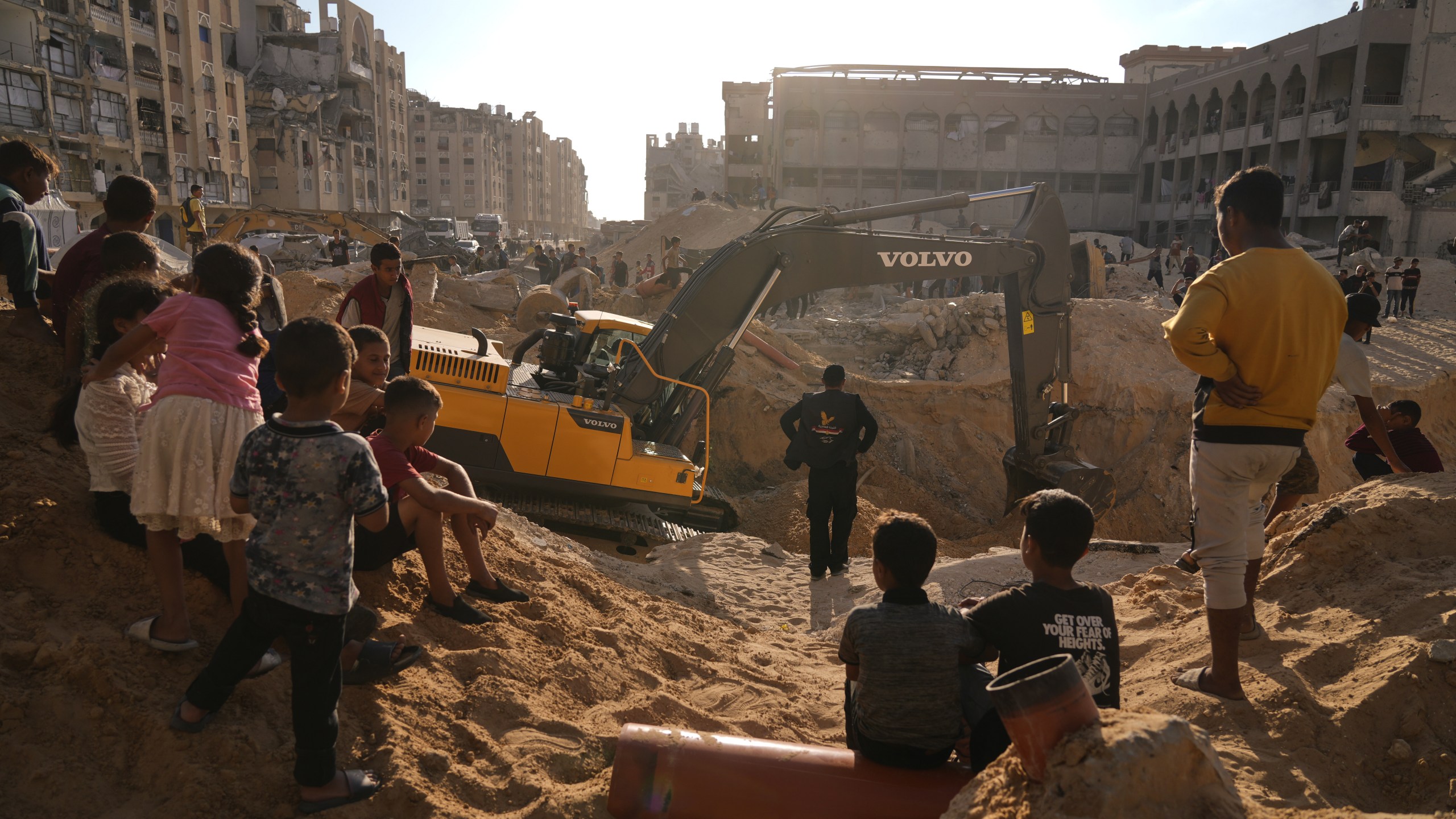 Palestinians watch machinery and some workers from Egypt searching for the bodies of hostages at Hamad City, in Khan Younis, southern Gaza Strip, Sunday, Oct. 26, 2025. (AP Photo/Jehad Alshrafi)