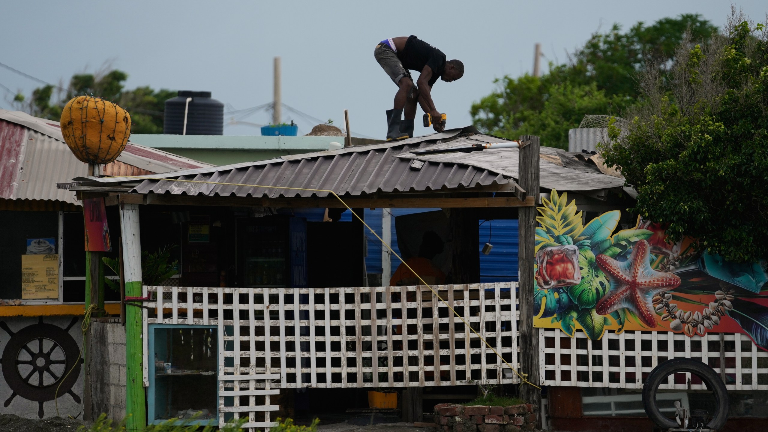 A man fortifies a roof ahead of the forecast arrival of Hurricane Melissa in Kingston, Jamaica, Sunday, Oct. 26, 2025. (AP Photo/Matias Delacroix)
