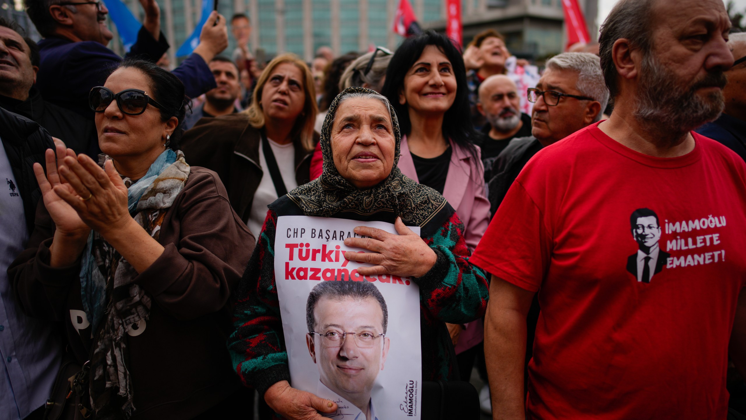 People listen to speeches during a rally in support of Istanbul's imprisoned opposition Mayor Ekrem Imamoglu as he appears for a hearing at the Caglayan courthouse, in Istanbul, Turkey, Sunday, Oct. 26, 2025. The poster with the photo of Imamoglu reads in Turkish: "Turkey will win". (AP Photo/Emrah Gurel)