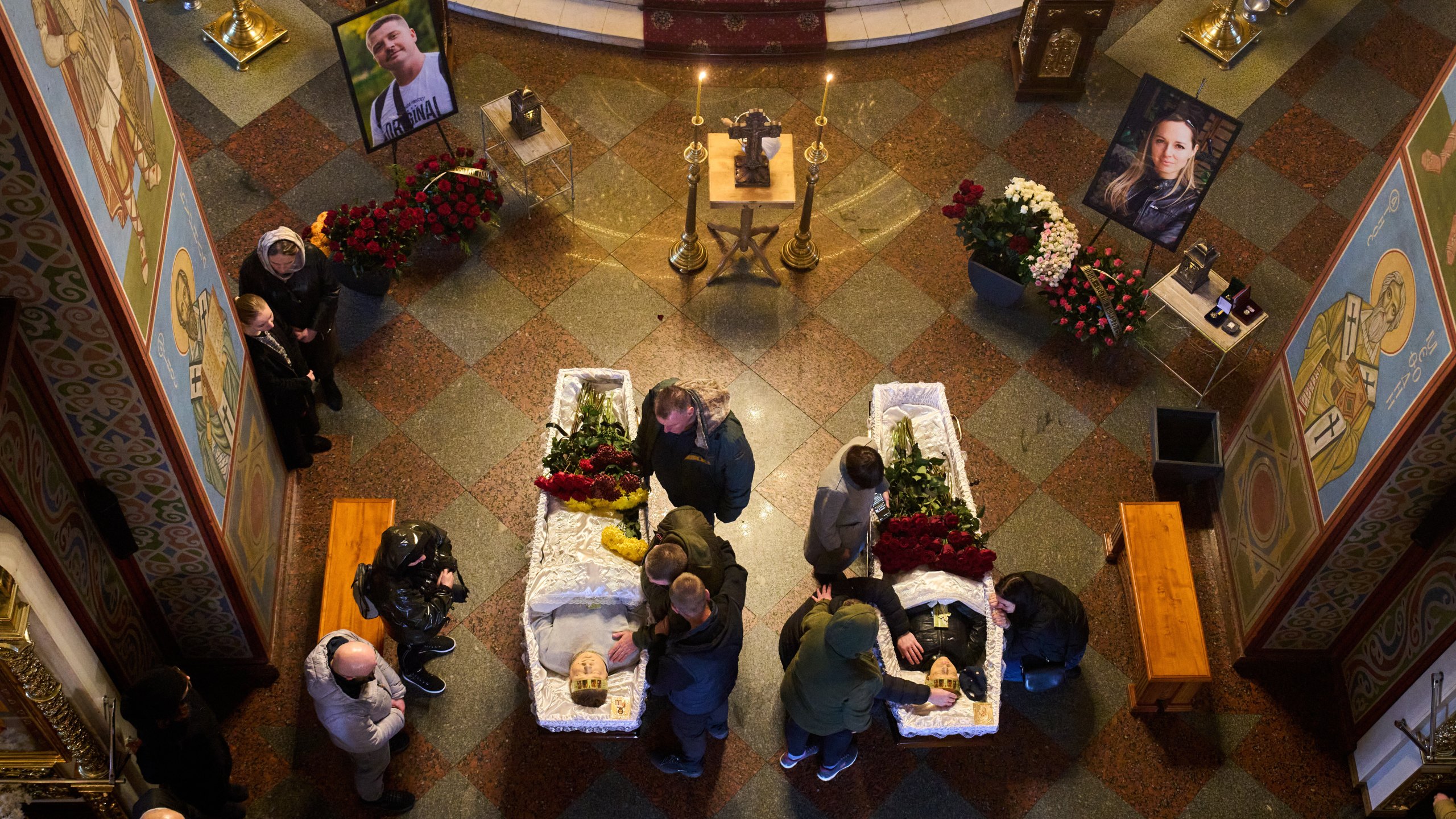 Relatives, colleagues and friends of two Ukrainian 43-year-old journalists Olena Hubanova, who worked under the pseudonym Alyona Gramova, and cameraman Yevhen Karmazin, who were killed on Thursday, Oct. 23, mourn over their coffins during a funeral service at St. Michael Monastery in Kyiv, Ukraine, Monday, Oct. 27, 2025. (AP Photo/Efrem Lukatsky)
