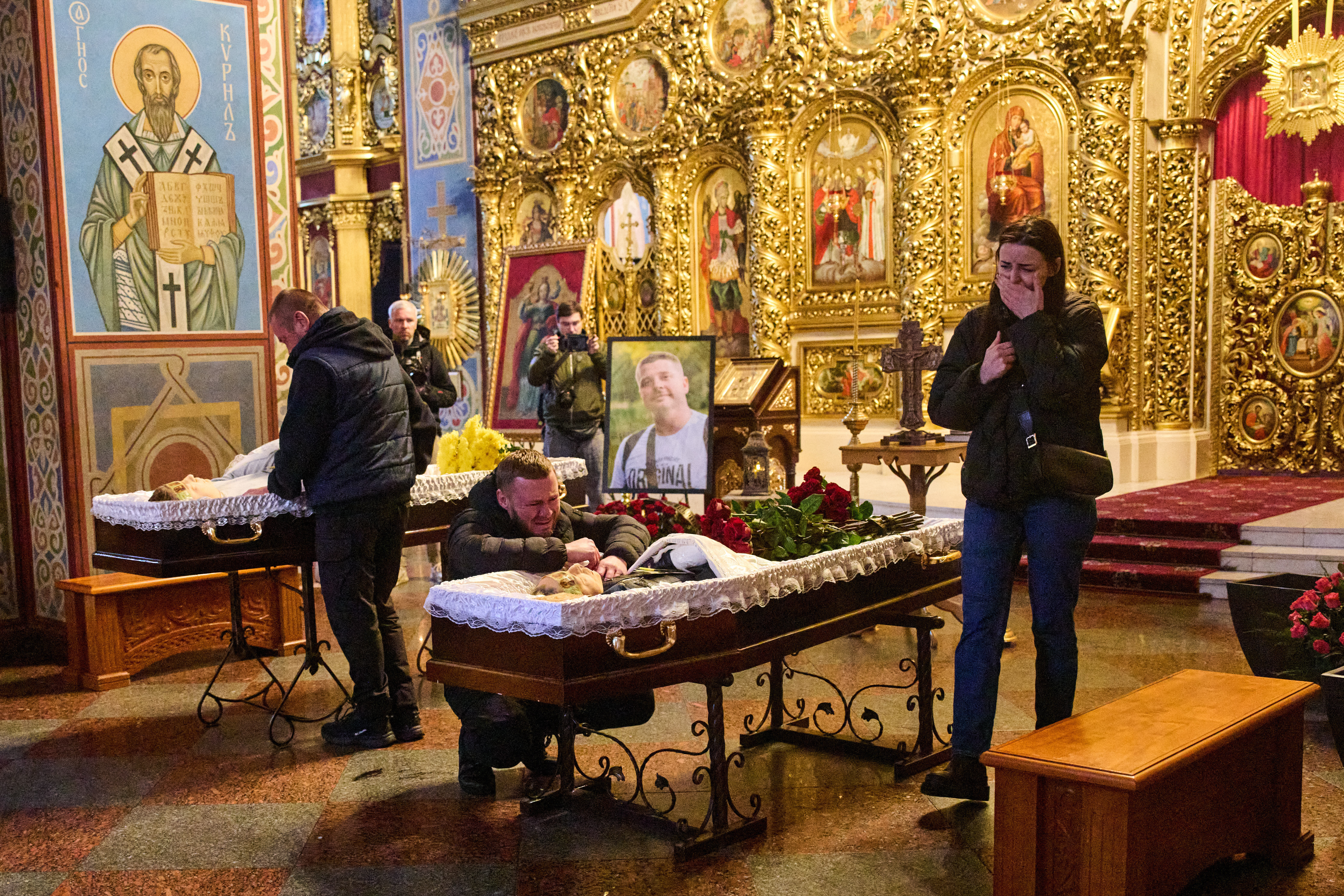 Relatives, colleagues and friends of two Ukrainian 43-year-old journalists Olena Hubanova, who worked under the pseudonym Alyona Gramova, and cameraman Yevhen Karmazin, who were killed on Thursday, Oct. 23, when a Russian Lancet drone hit their vehicle in Ukraine's Kramatorsk around 20 kilometres from the front line, mourn over their coffins during a funeral service at St. Michael Monastery in Kyiv, Ukraine, Monday, Oct. 27, 2025. (AP Photo/Efrem Lukatsky)