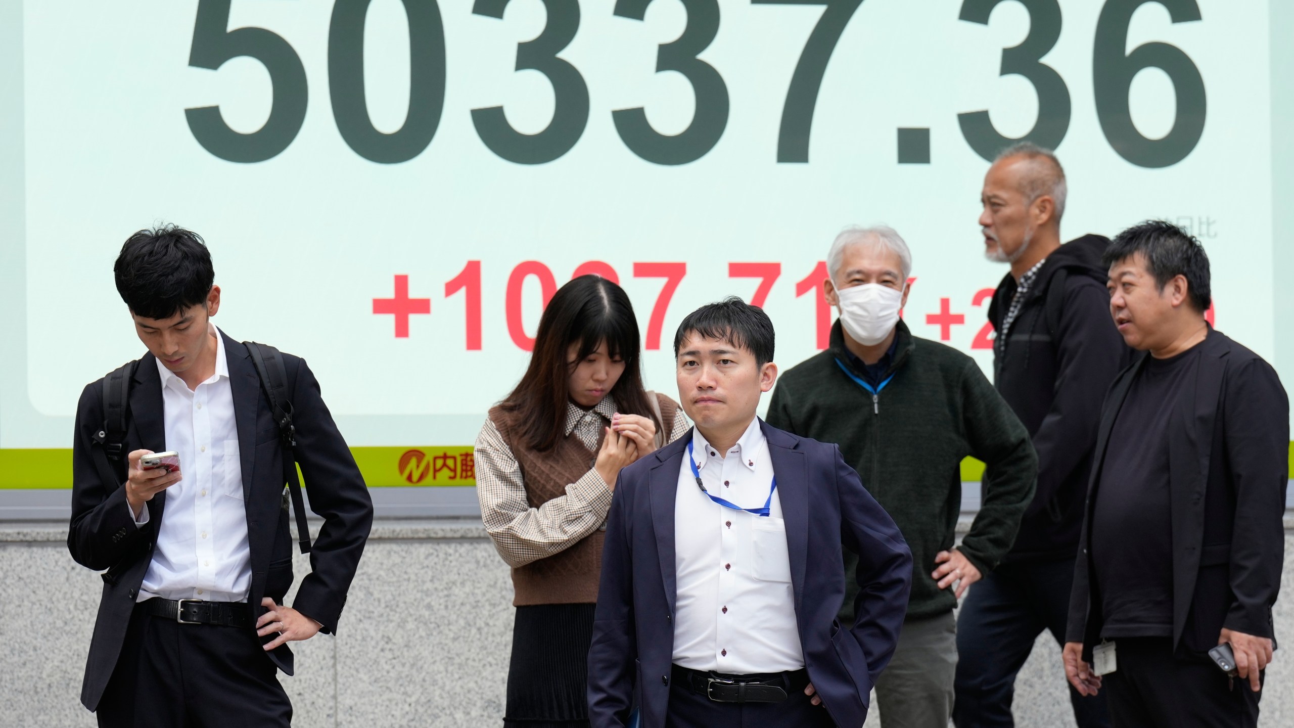 People stand in front of an electronic stock board showing Japan's Nikkei index at a securities firm Monday, Oct. 27, 2025, in Tokyo. (AP Photo/Eugene Hoshiko)