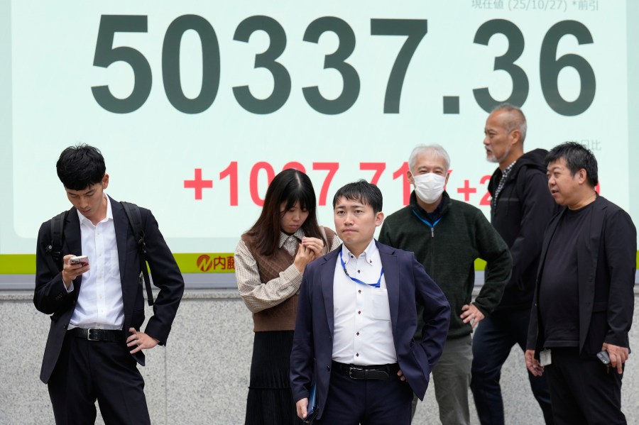 People stand in front of an electronic stock board showing Japan's Nikkei index at a securities firm Monday, Oct. 27, 2025, in Tokyo. (AP Photo/Eugene Hoshiko)