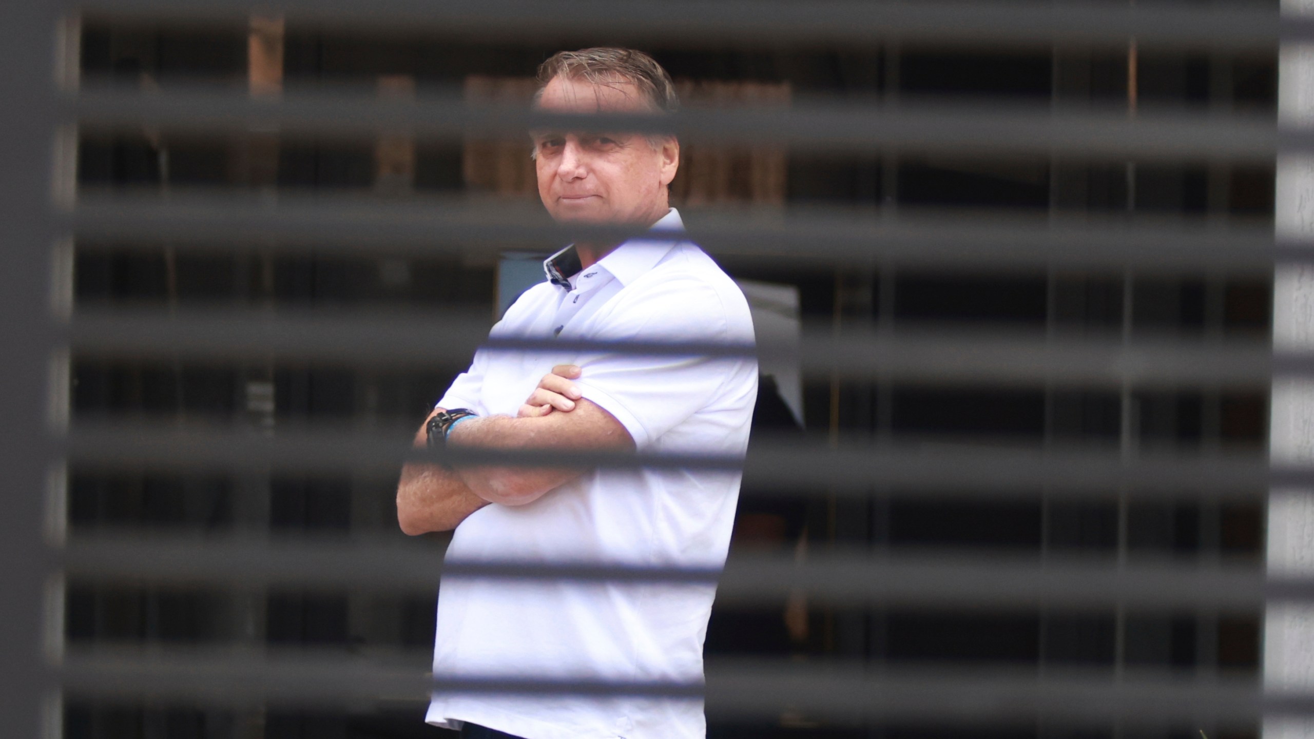 FILE - Brazil's former President Jair Bolsonaro stands at the entrance of his home while he is under house arrest in Brasilia, Brazil, Sept. 2, 2025. (AP Photo/Luis Nova, File)