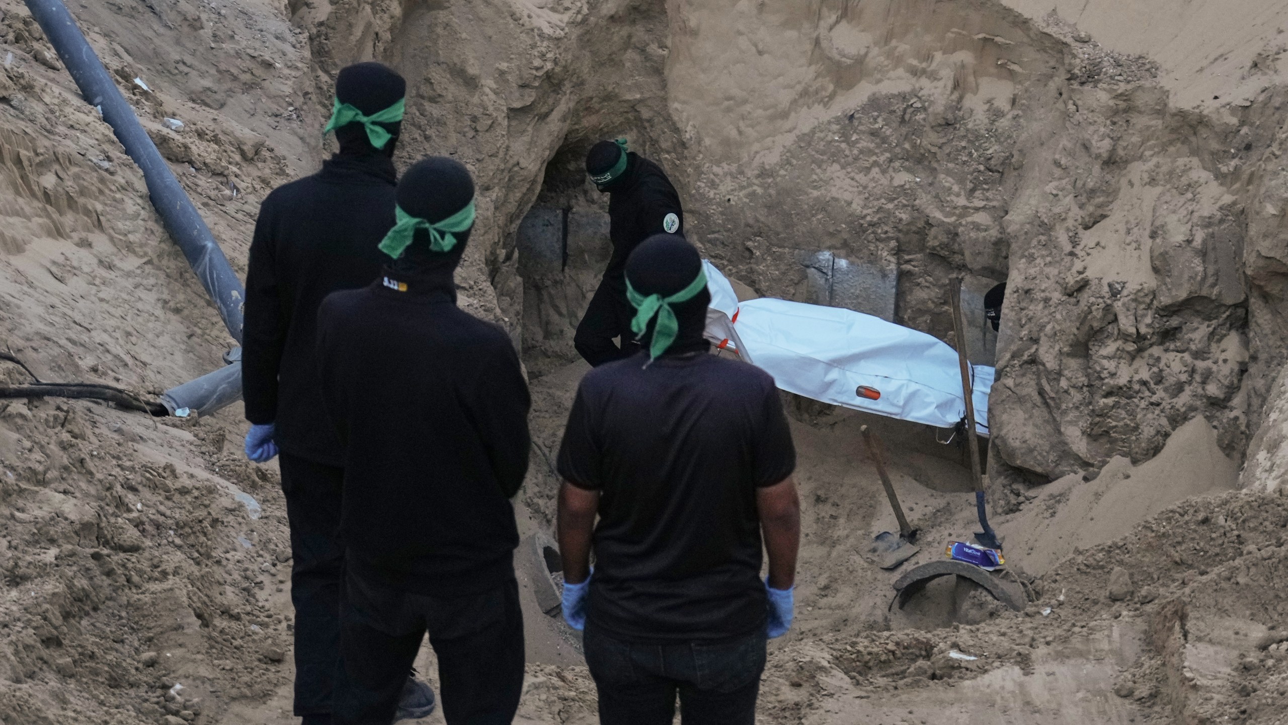 Hamas militants carry a white bag believed to contain a body, after retrieving it from a tunnel during a search for the remains of hostages in Hamad City, Khan Younis, in southern Gaza, Tuesday, Oct. 28, 2025. (AP Photo/Jehad Alshrafi)