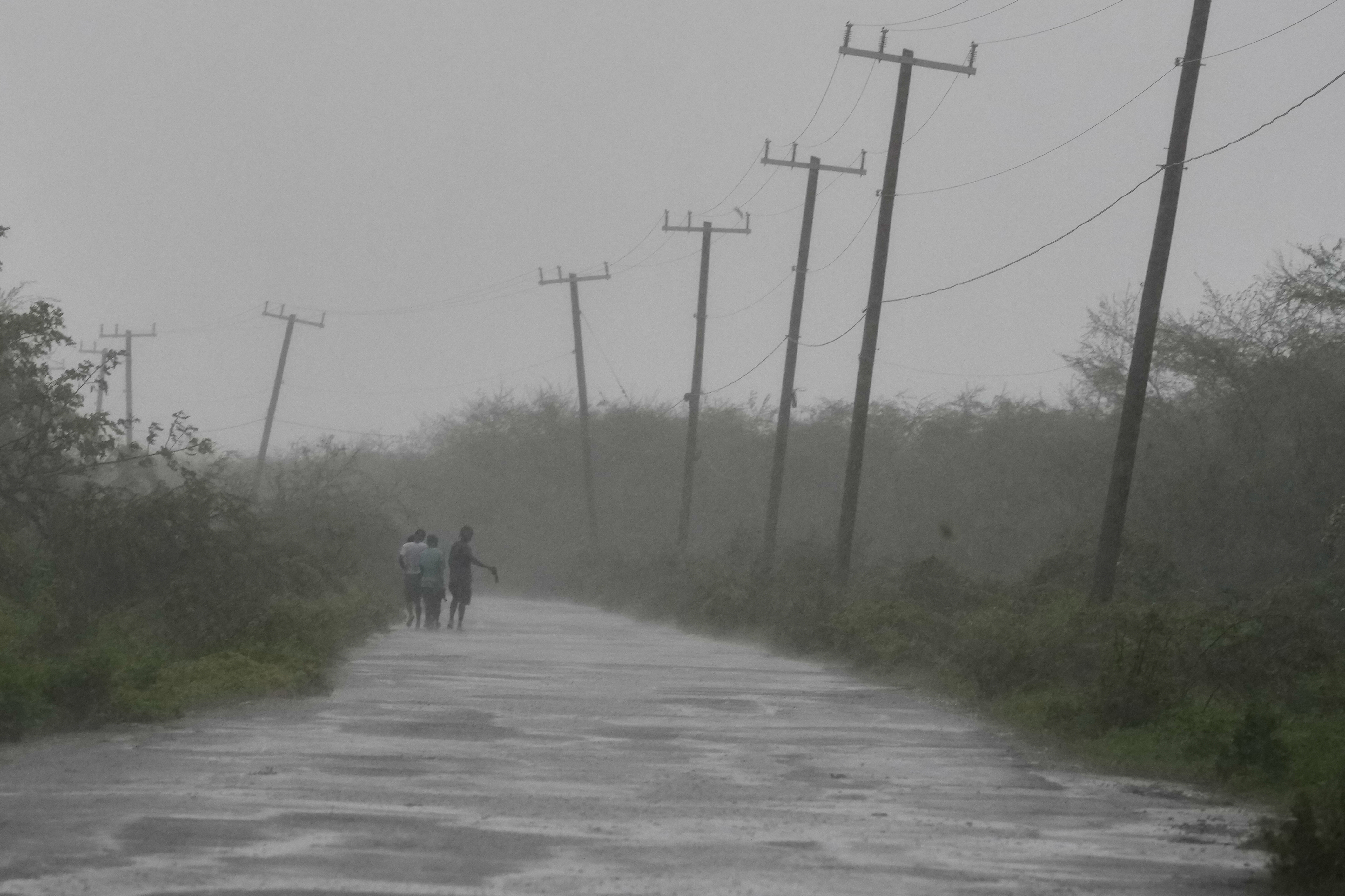 People walk along a road during the passing of Hurricane Melissa in Rocky Point, Jamaica, Tuesday, Oct. 28, 2025. (AP Photo/Matias Delacroix)