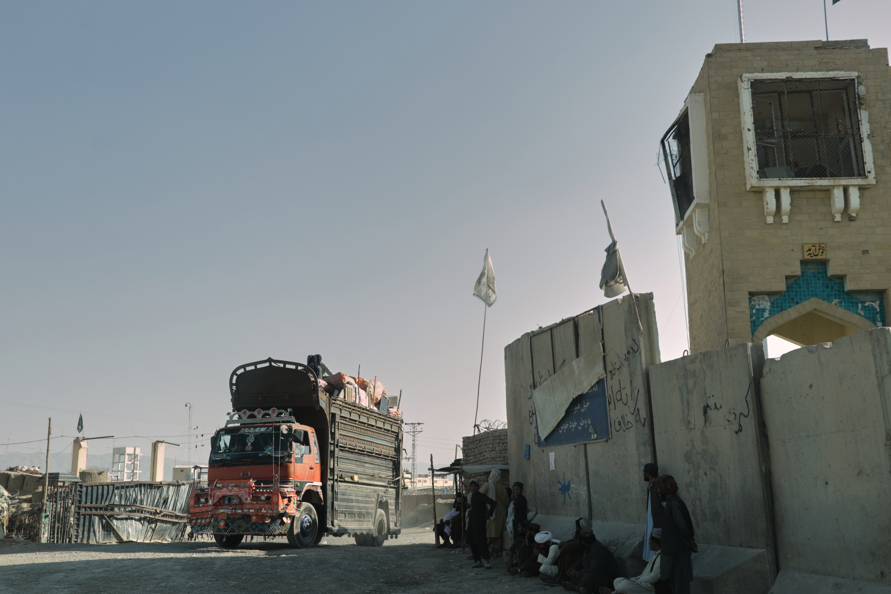 People wait near the closed gate at the Spin Boldak border crossing with Pakistan, after the border was shut for nearly two weeks following clashes between Afghan and Pakistani forces, in Kandahar province, Afghanistan, Thursday, Oct. 23, 2025. (AP Photo/Sibghatullah)