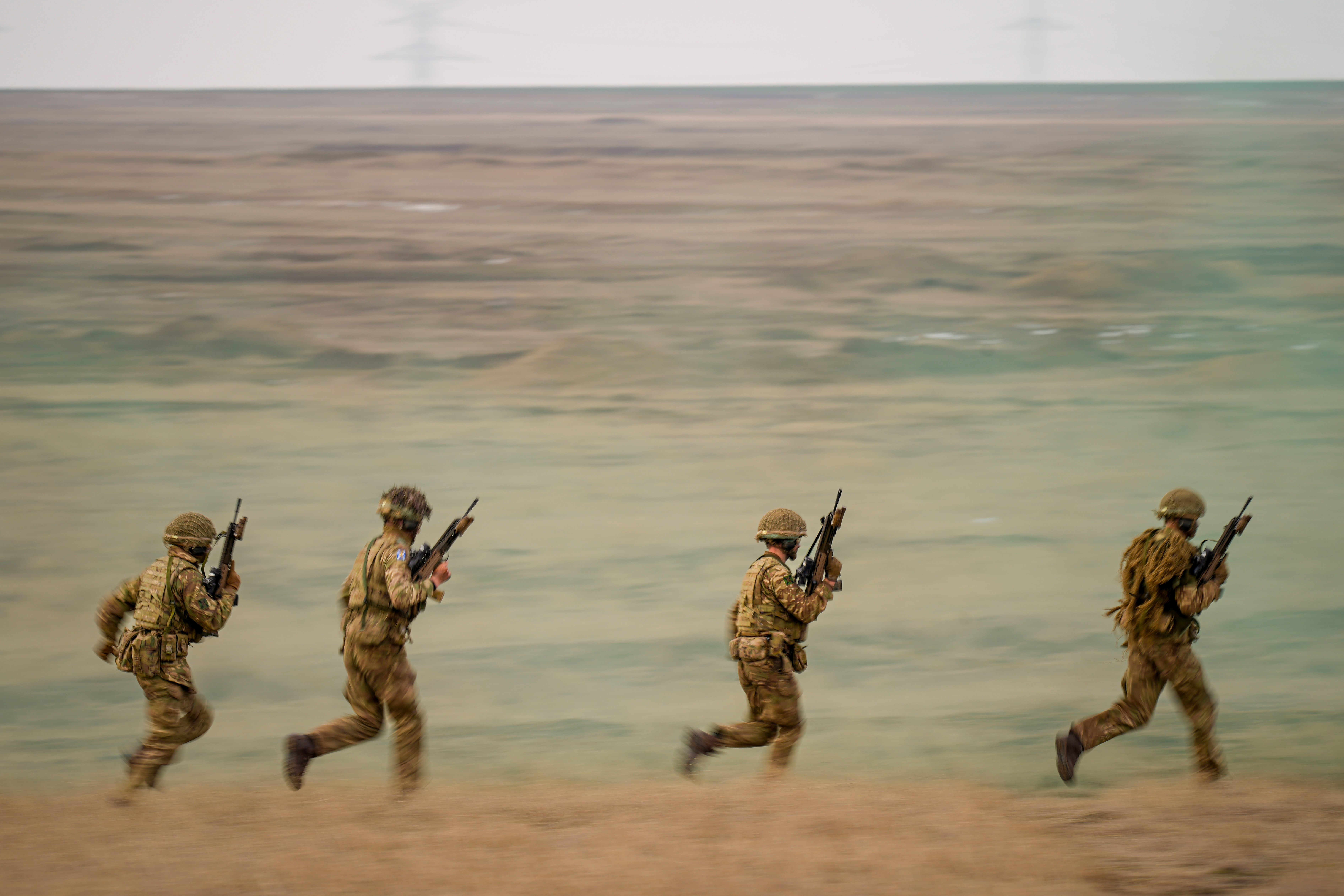 FILE- Servicemen run during the Steadfast Dart 2025 exercise, involving some 10,000 troops in three different countries from nine nations, representing the largest NATO operation planned this year, at a training range in Smardan, eastern Romania, Wednesday, Feb. 19, 2025. (AP Photo/Vadim Ghirda, file)