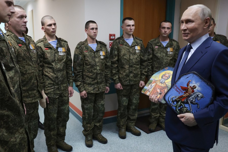 President Vladimir Putin holds Russian Orthodox icons as he meets with soldiers wounded in action in Ukraine, at the the Mandryk Central Military Clinical Hospital, in Moscow, Russia, Wednesday, Oct. 29, 2025. (Vyacheslav Prokofyev, Sputnik, Kremlin Pool Photo via AP)