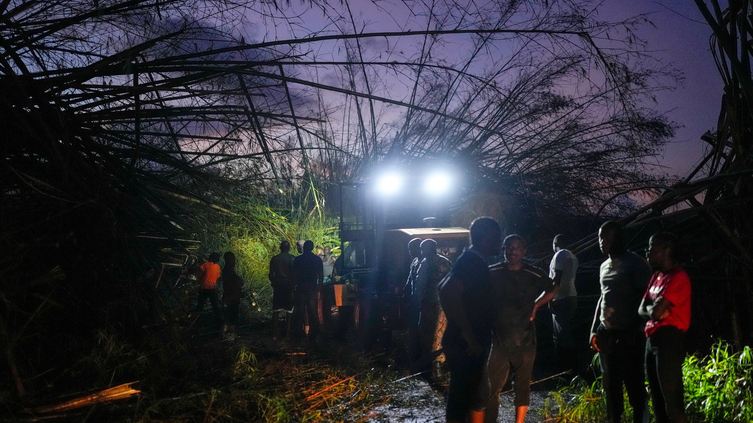 Workers clear downed trees and debris to make way for a convoy carrying aid to Black River, which was hit by Hurricane Melissa, as it moves through Holland Bamboo, Jamaica, Wednesday, Oct. 29, 2025. (AP Photo/Matias Delacroix)