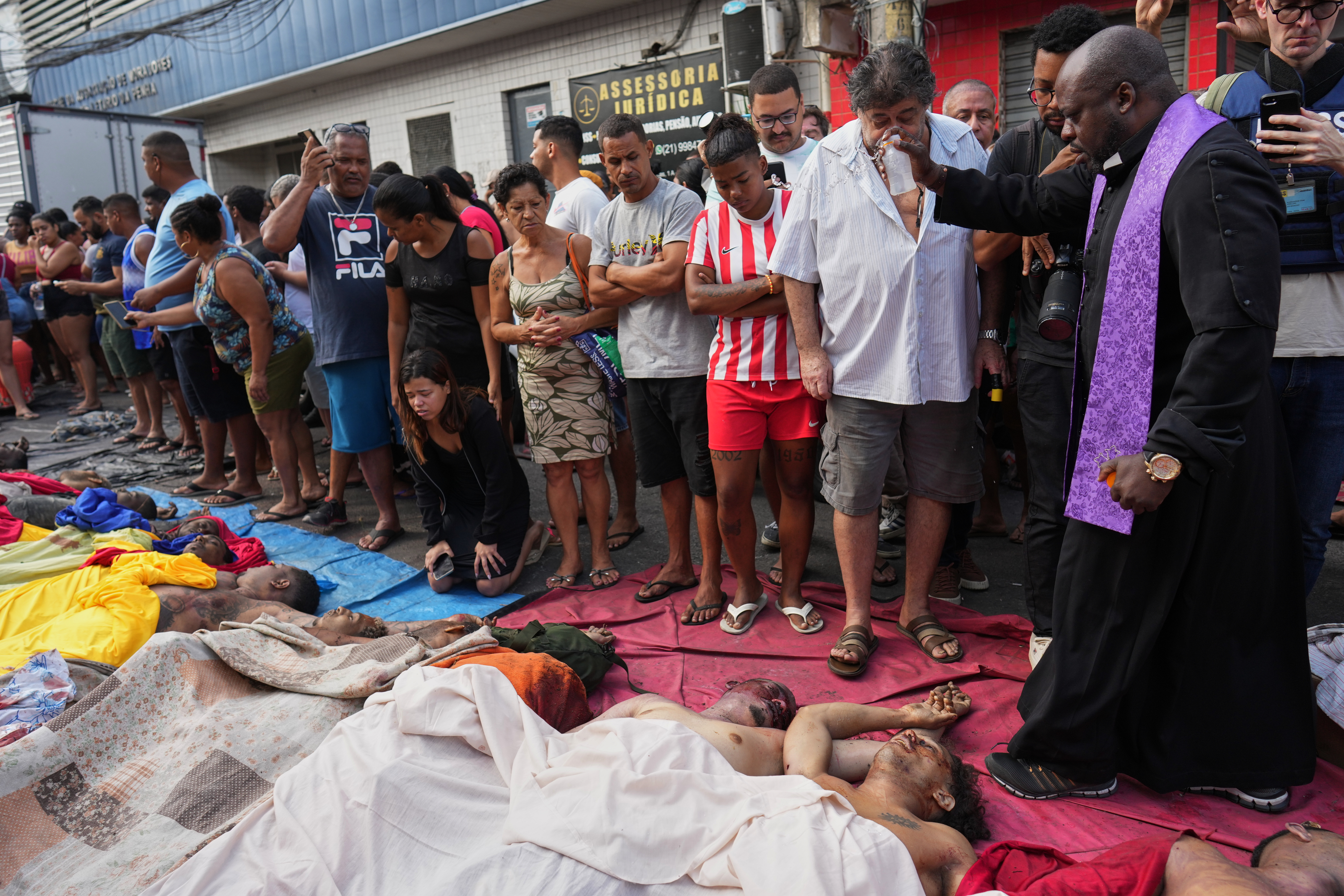 FILE - A priest blesses the bodies of people killed the day before during a police raid targeting the Comando Vermelho gang in the Complexo da Penha favela of Rio de Janeiro, Brazil, Wednesday, Oct. 29, 2025. (AP Photo/Silvia Izquierdo, File)